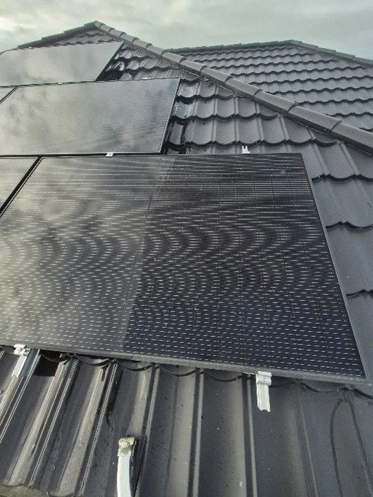 Solar panels installed on a black tiled roof.