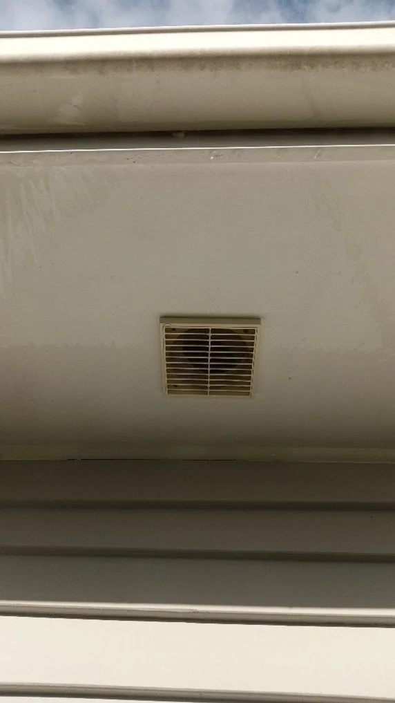 Ceiling vent in a white ceiling with a window frame visible at the top.