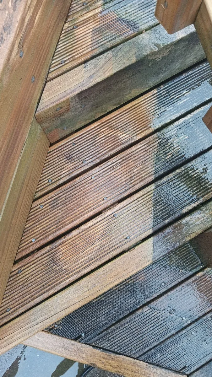 Close-up of wet wooden deck with water reflections and shadows.