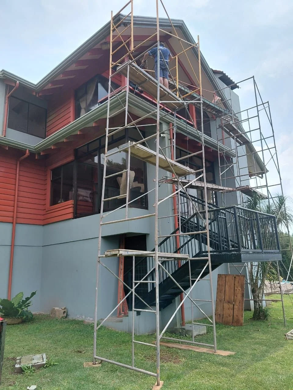 Edificio en construcción con andamios y trabajador en la parte superior