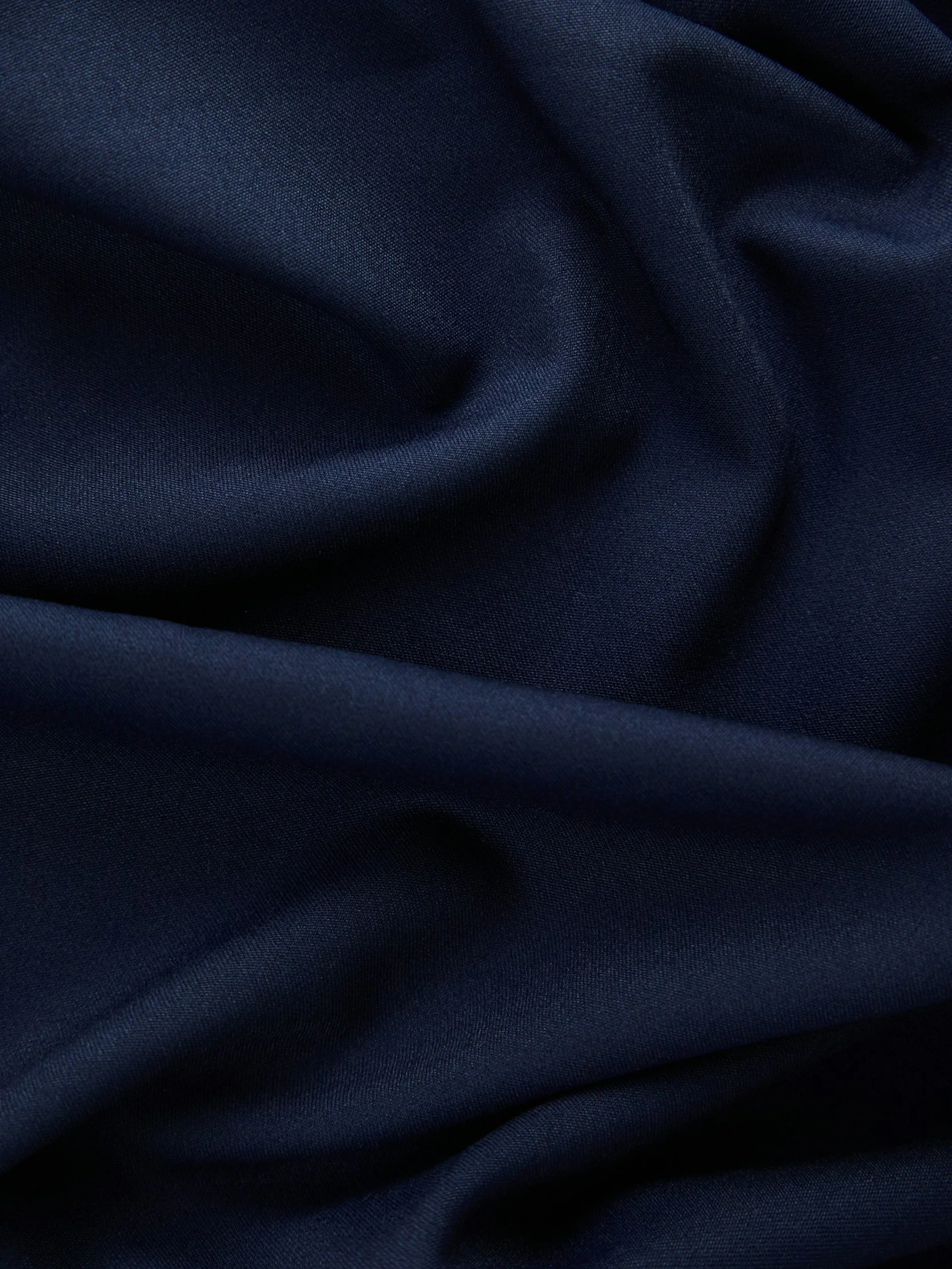 Close-up of dark navy blue fabric with visible texture and folds.