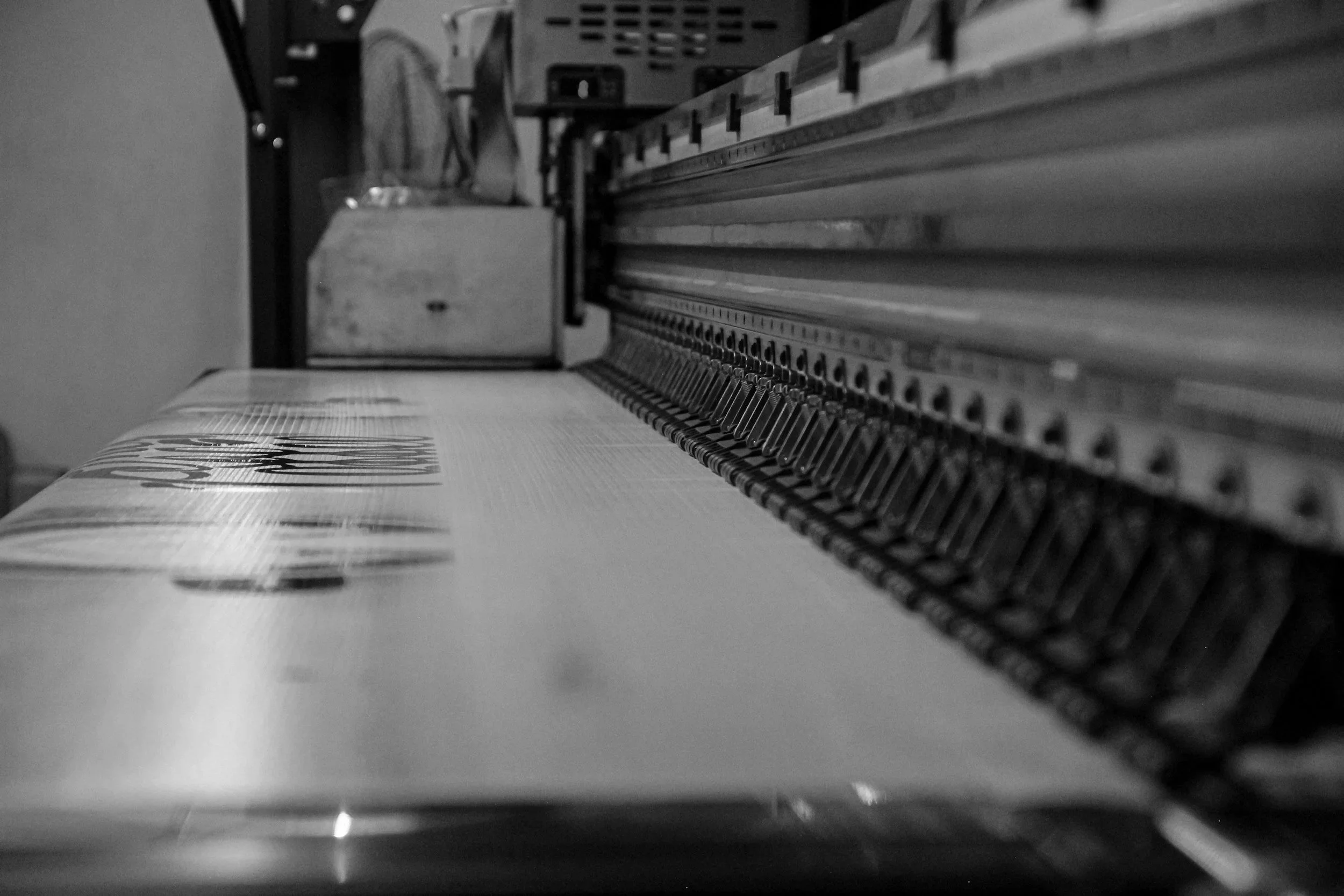 Close-up of a printing machine with a roll of printed material passing through it, in black and white.
