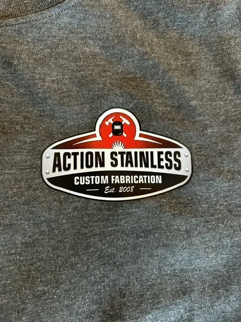 A logo for Action Stainless on a gray fabric background.