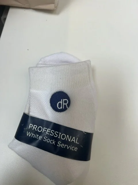 A white sock with a blue circular logo and text, labeled as 'PROFESSIONAL White Sock Service'.