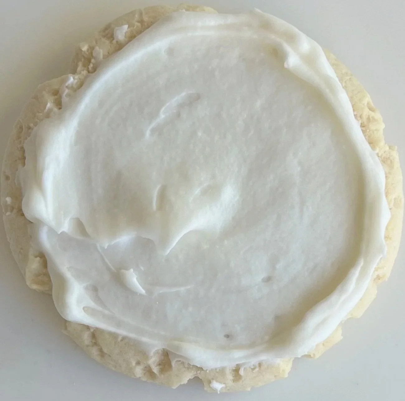 A round cookie with white icing on top.