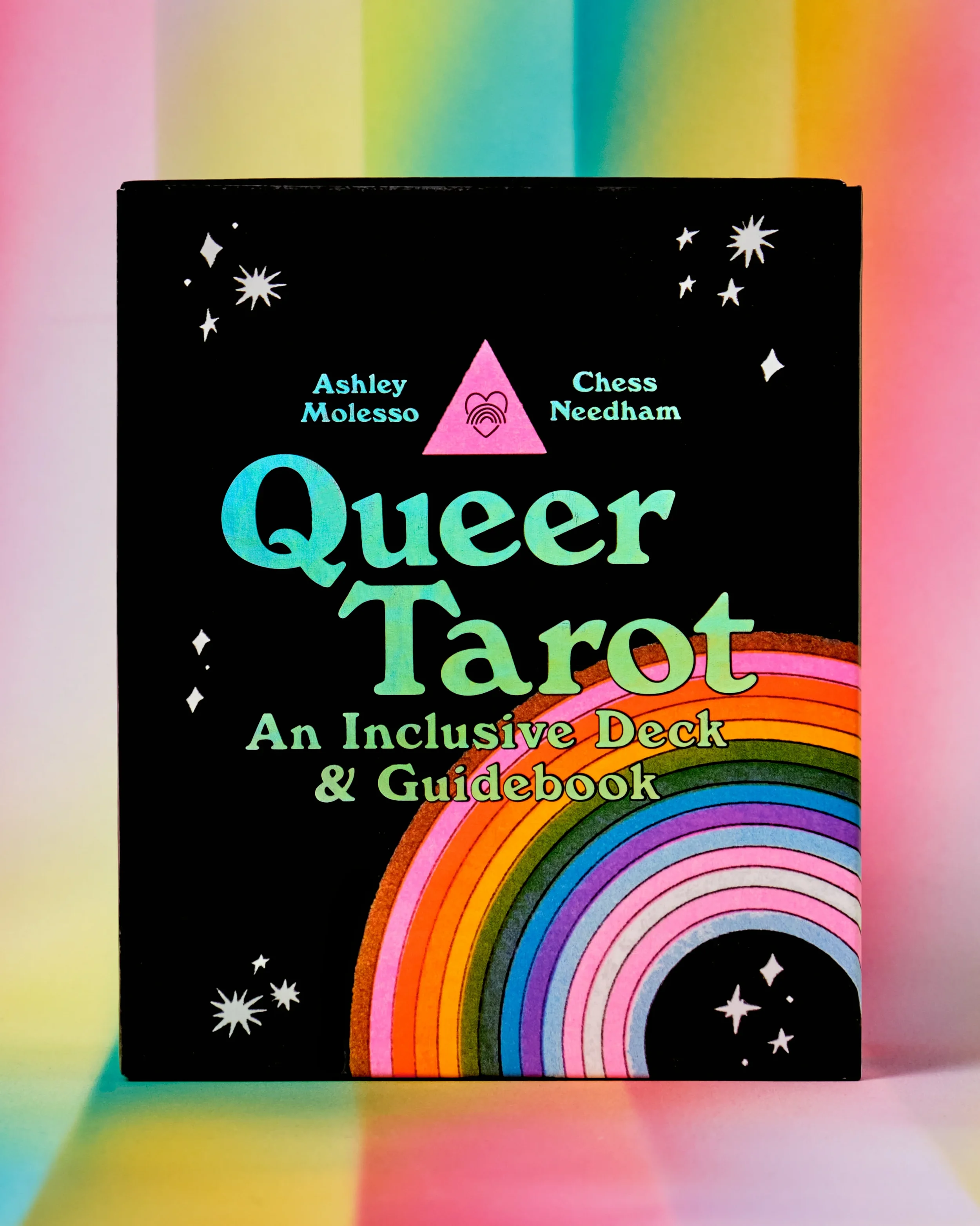 Cover of a book titled 'Queer Tarot: An Inclusive Deck & Guidebook' with a black background, stars, and a rainbow semi-circle design.