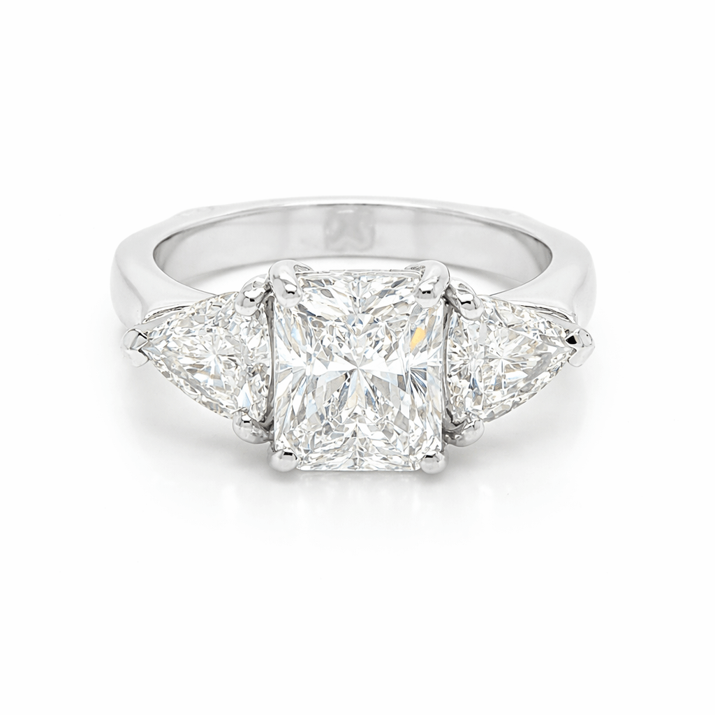 Trilogy ring set with an emerald cut diamond and trilliant cut diamonds in white gold.