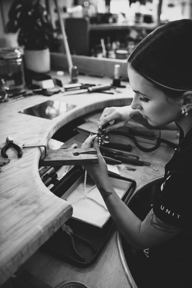 A jeweller working on restringing a pearl necklace.
