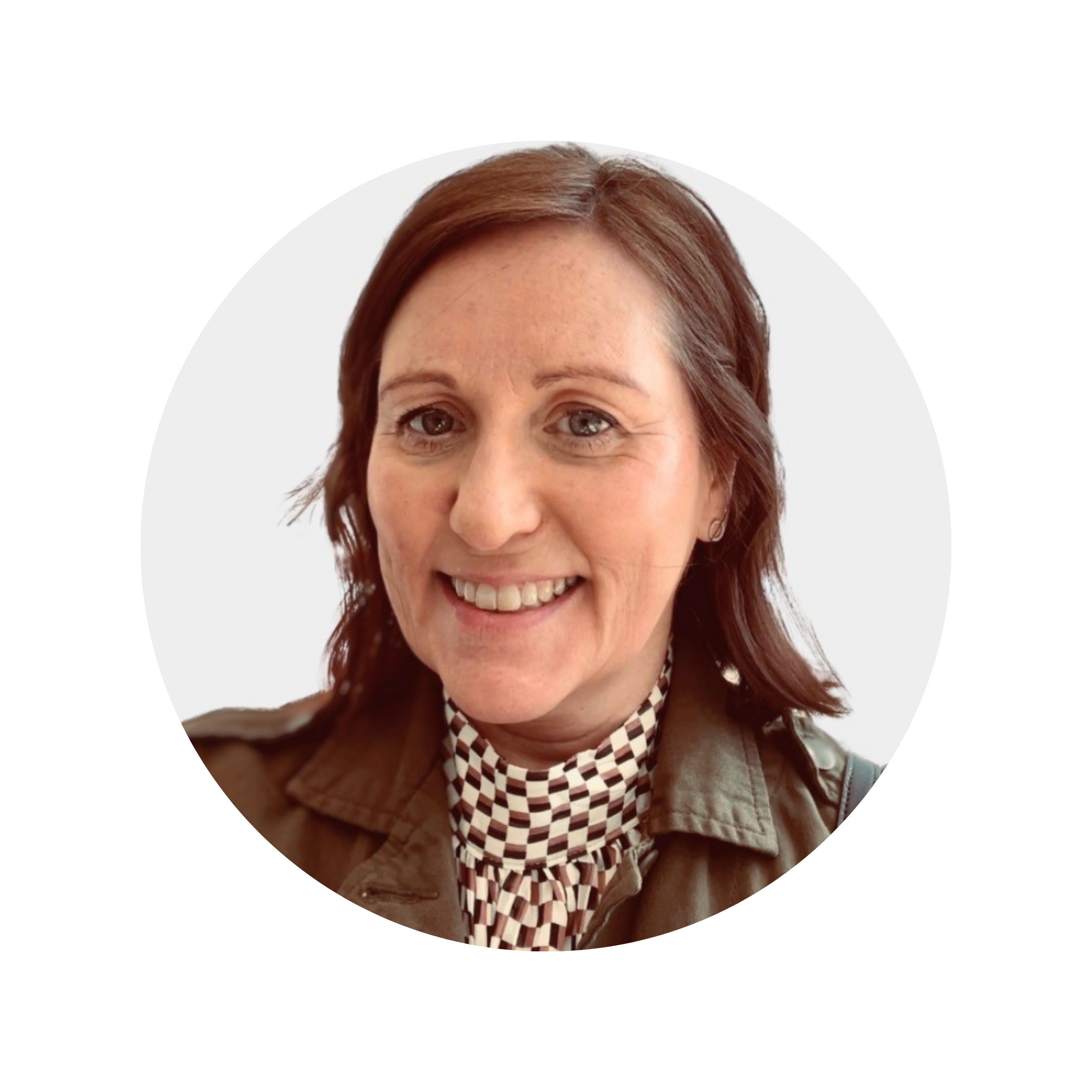 A woman with auburn hair and a checkered scarf wearing a tan jacket, smiling.