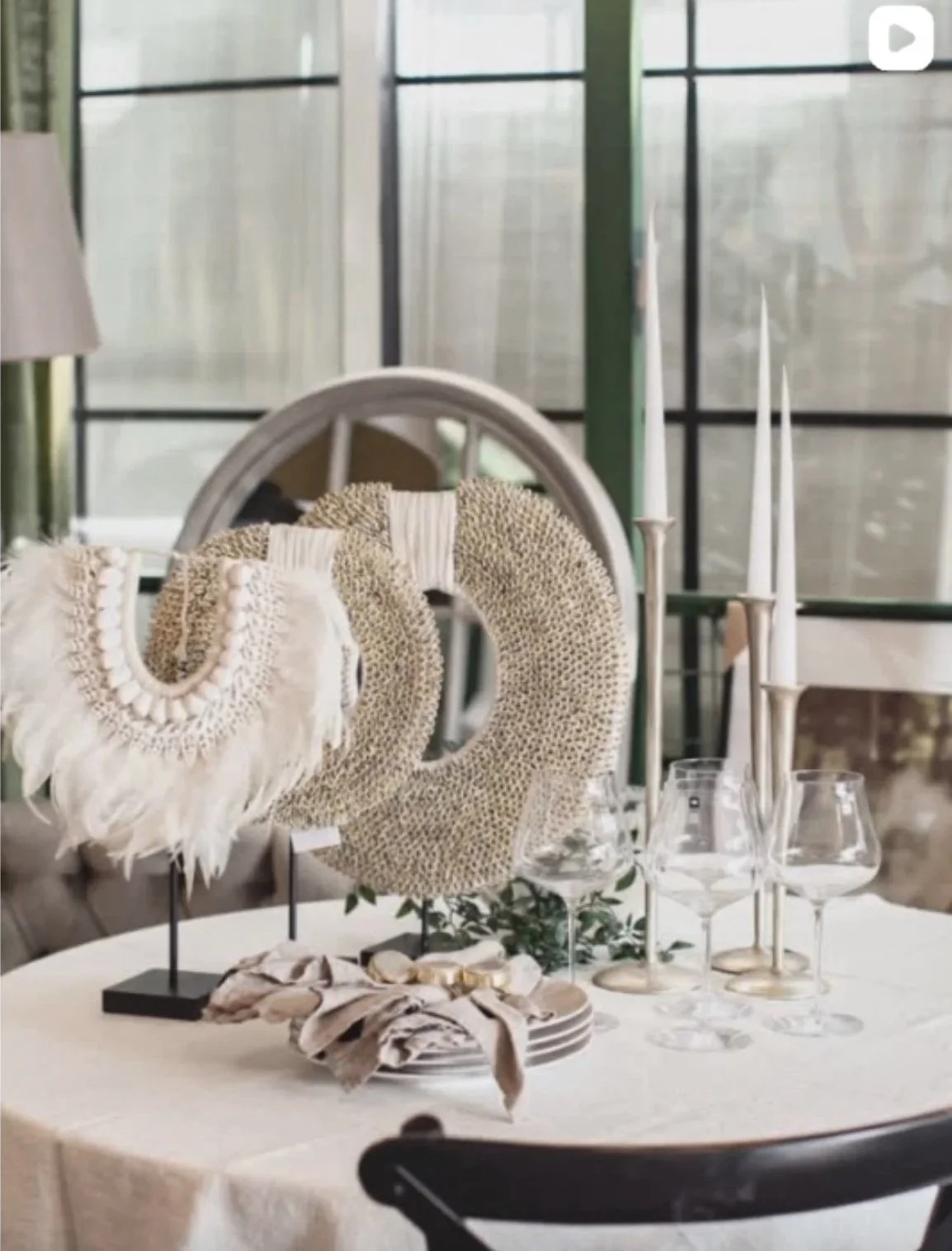 Decorative table setting with candles, glassware, and fabric accessories in a softly lit room with denim paneled walls.