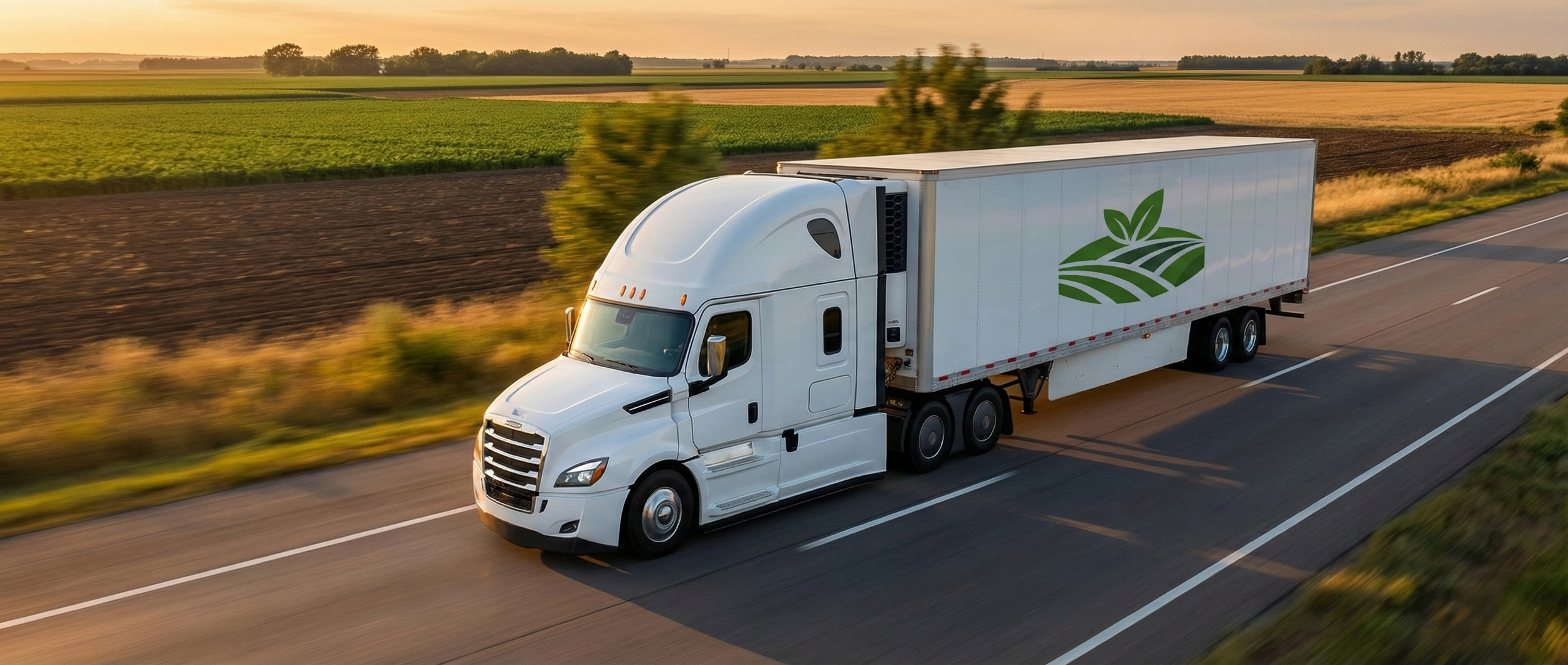 White refrigerated semi-truck with the R&R Produce & Distribution leaf logo driving on a highway past farmland at sunset.