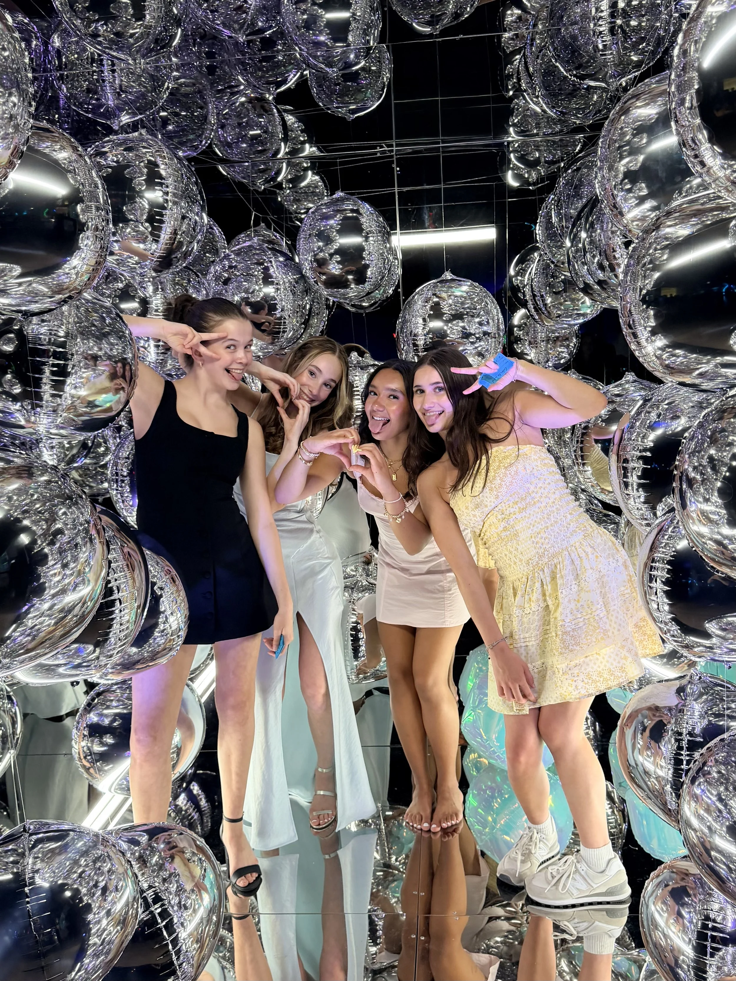 girls having fun and posing in a silly way inside the mirror cube photo booth
