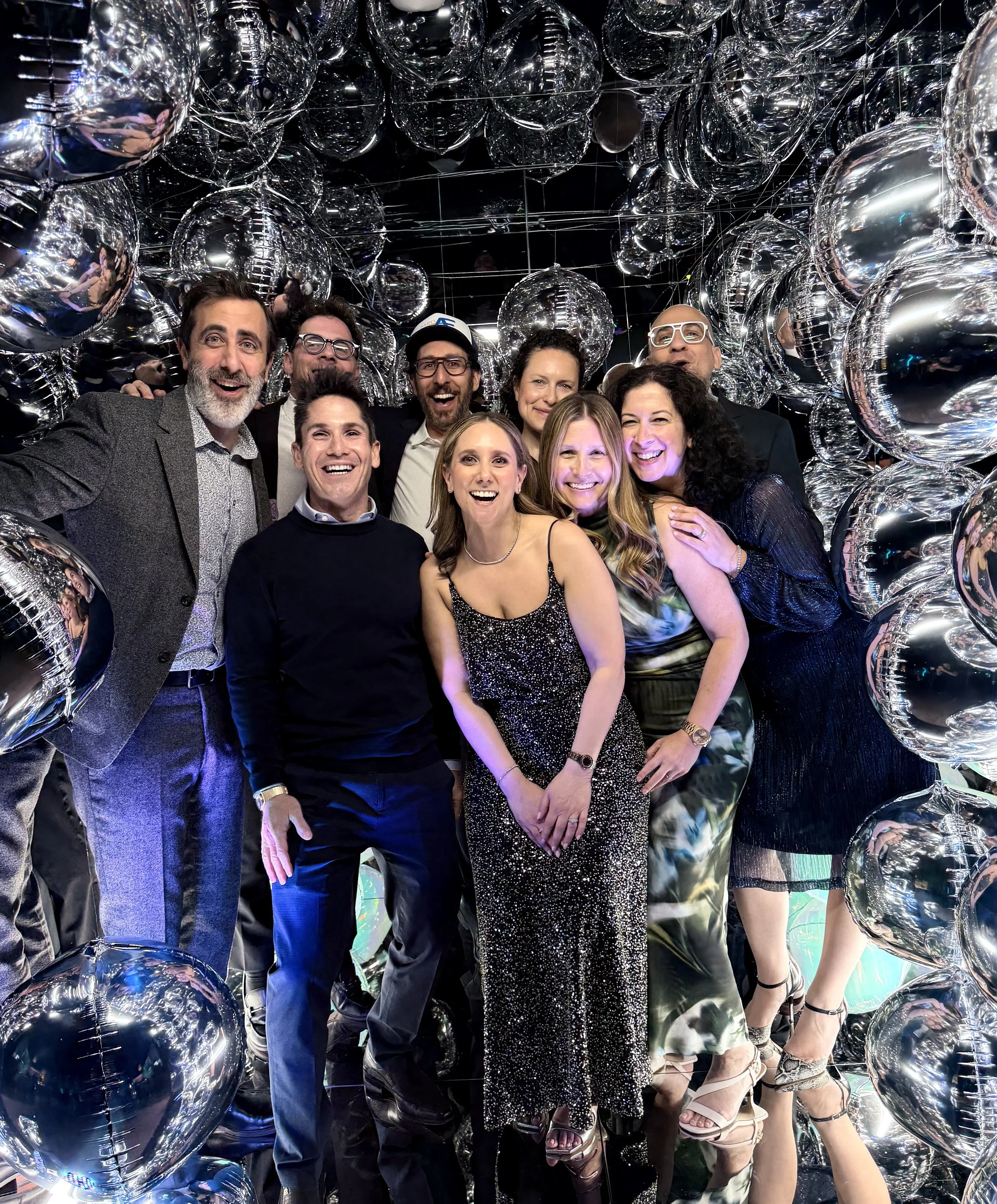 Happy group of people, smiling and having fun at a bar mitzvah inside a mirror cube booth