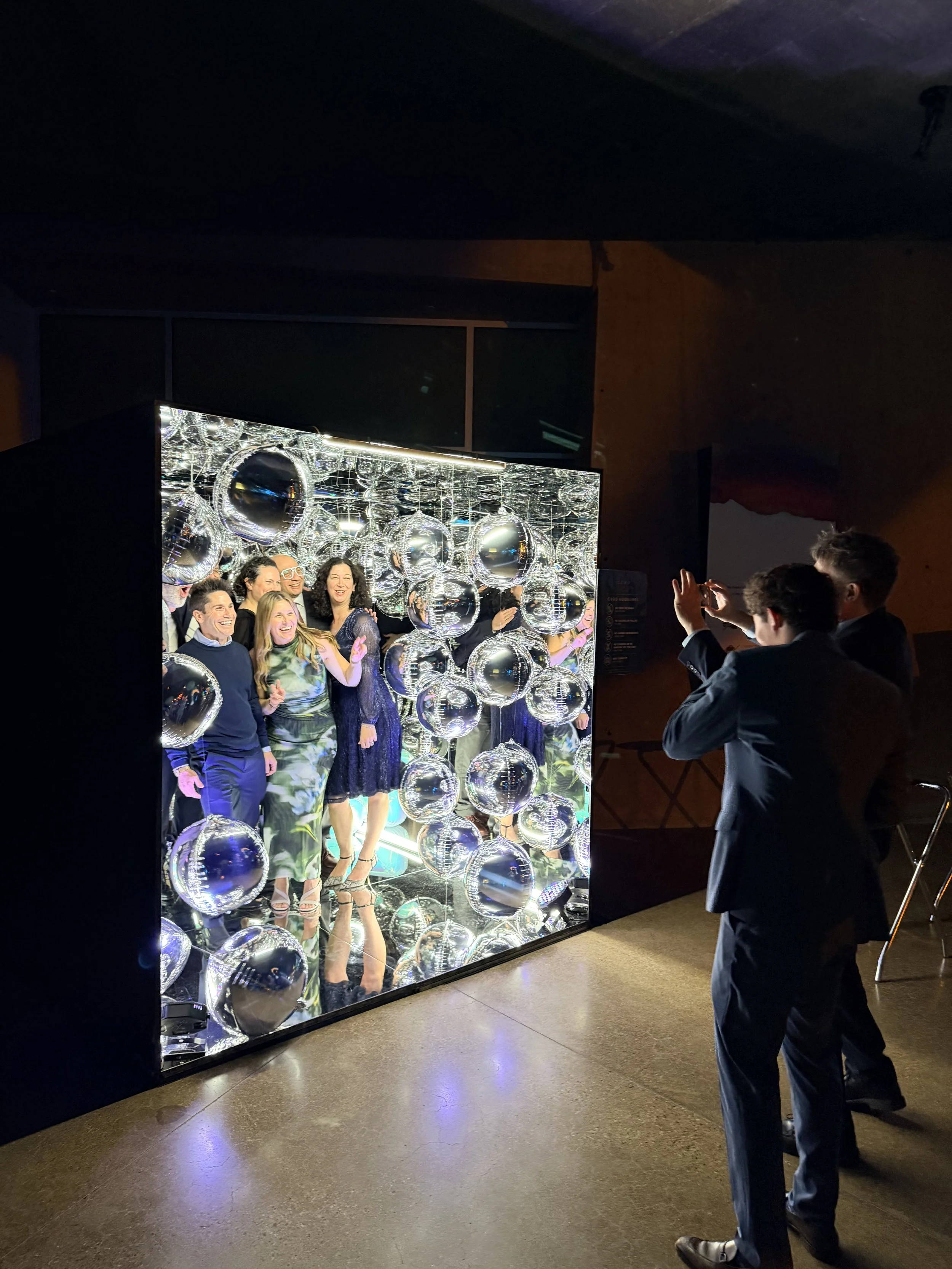 Taking pictures of a group of smiling people at a bar mitzvah inside the mirror photo cube booth