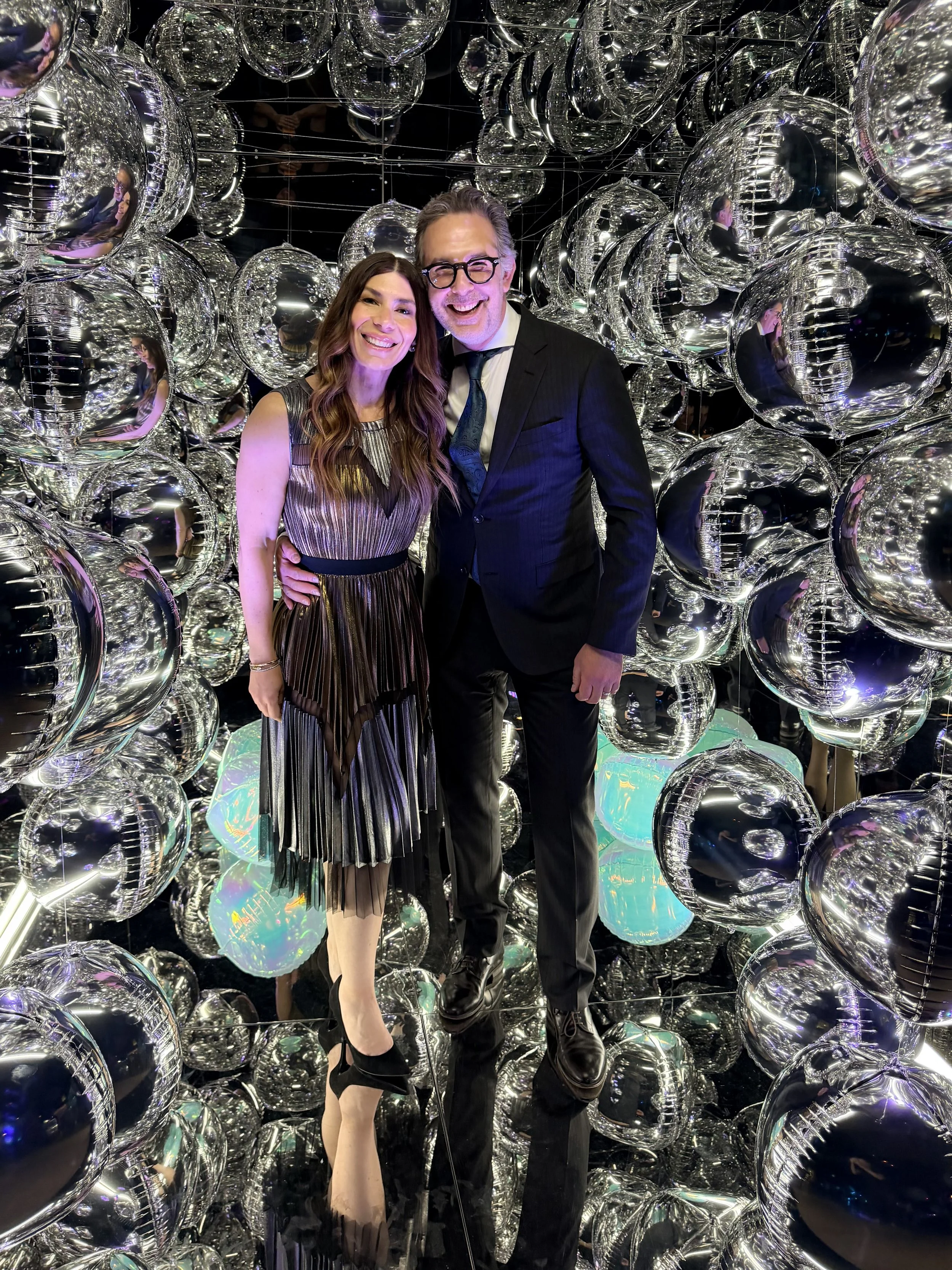 a man and woman smiling, looking happy inside the mirror photo cube booth