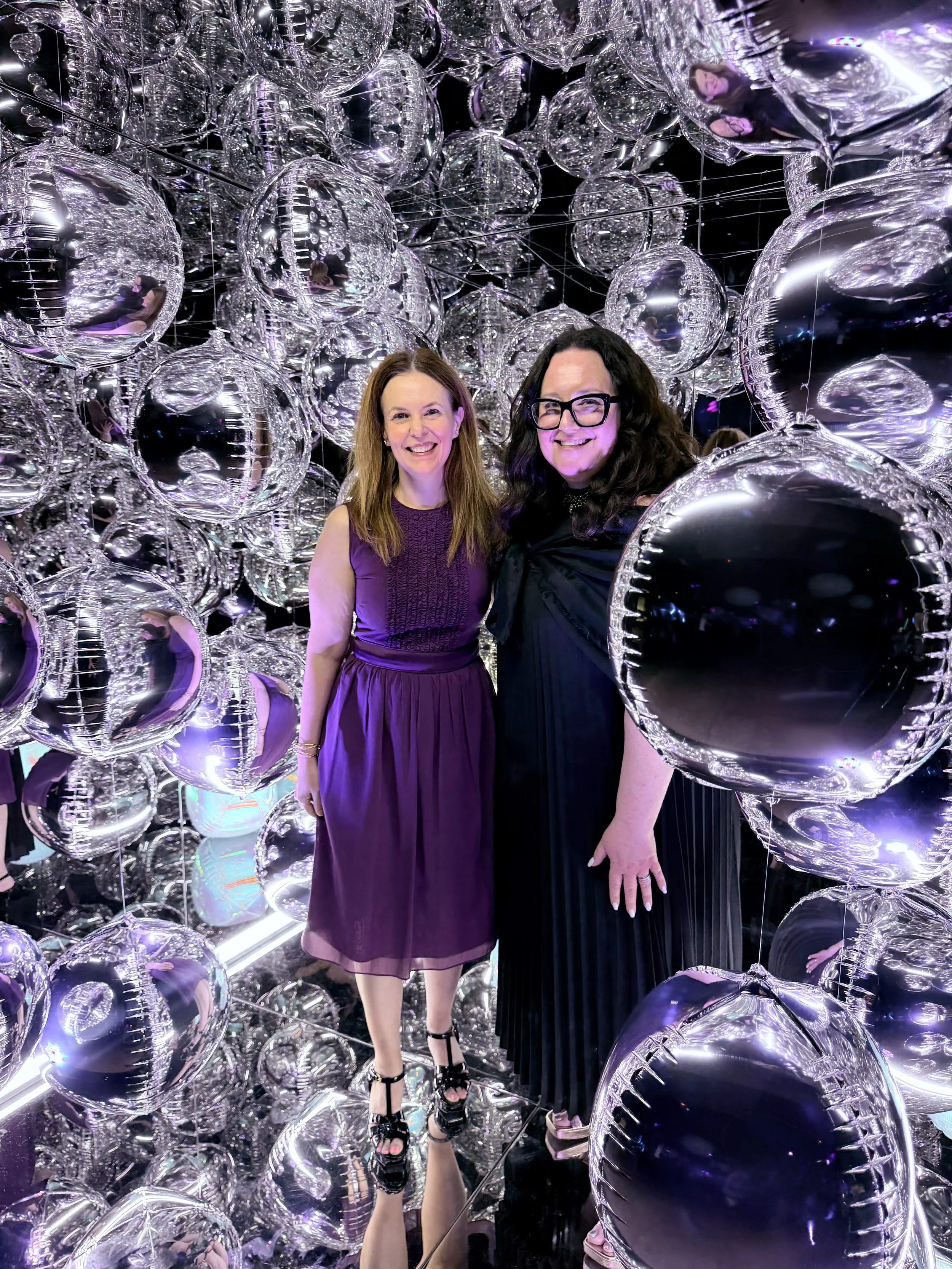 two women smiling at a bar mitzvah and looking at the camera at an angle inside the mirror photo cube booth