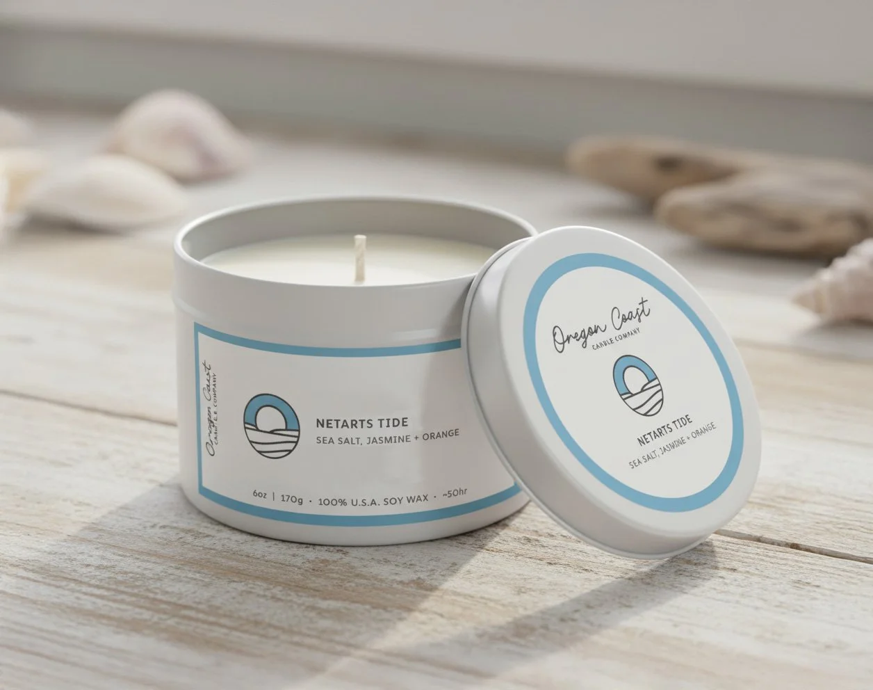 White candle in a labeled container with seashells in the background.