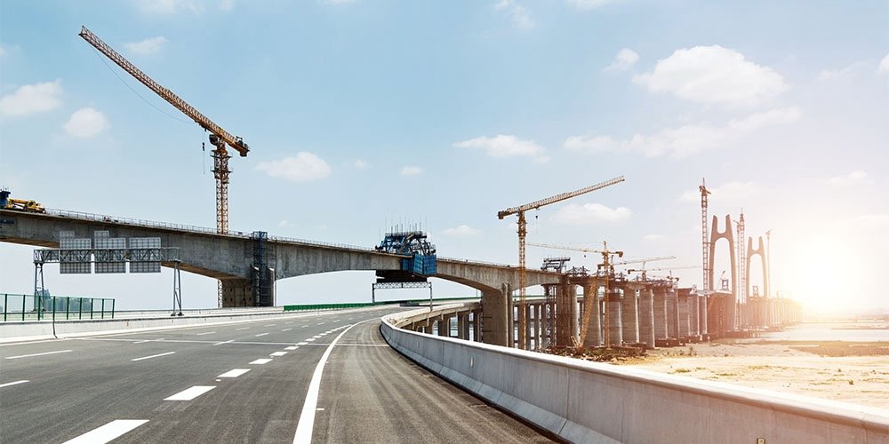 Under construction bridge with cranes on a clear, sunny day