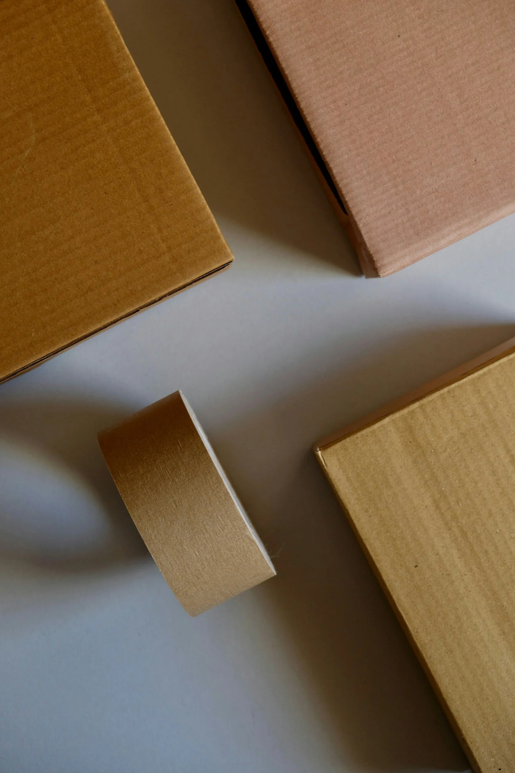 Several cardboard boxes of varying sizes, some are pink and others are brown, on a light-colored surface.
