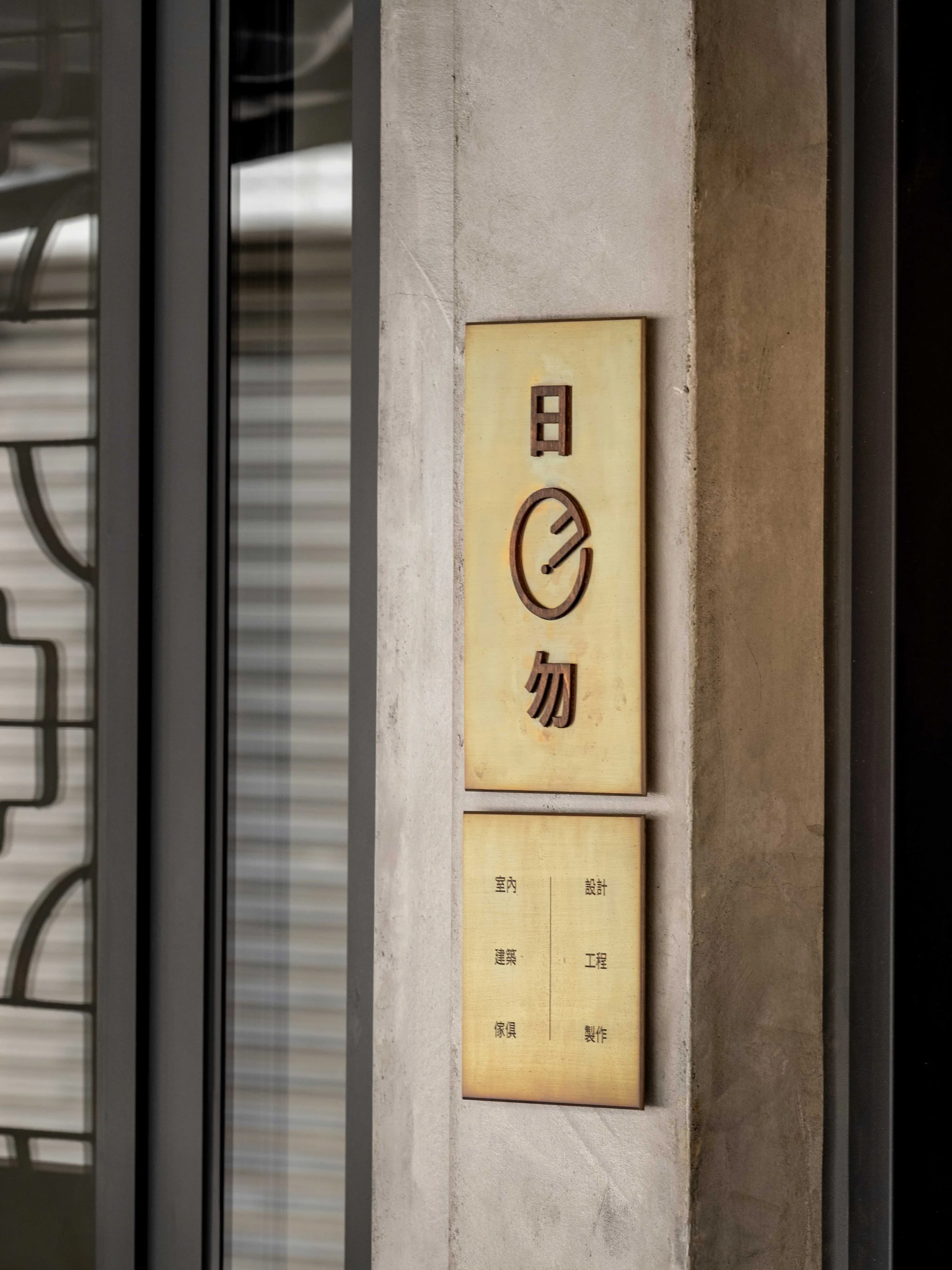 高雄辦公室室內裝修細節：日勿設計選擇以黃銅與木頭的紋理作為招牌，固定在水泥粉光的牆面上。