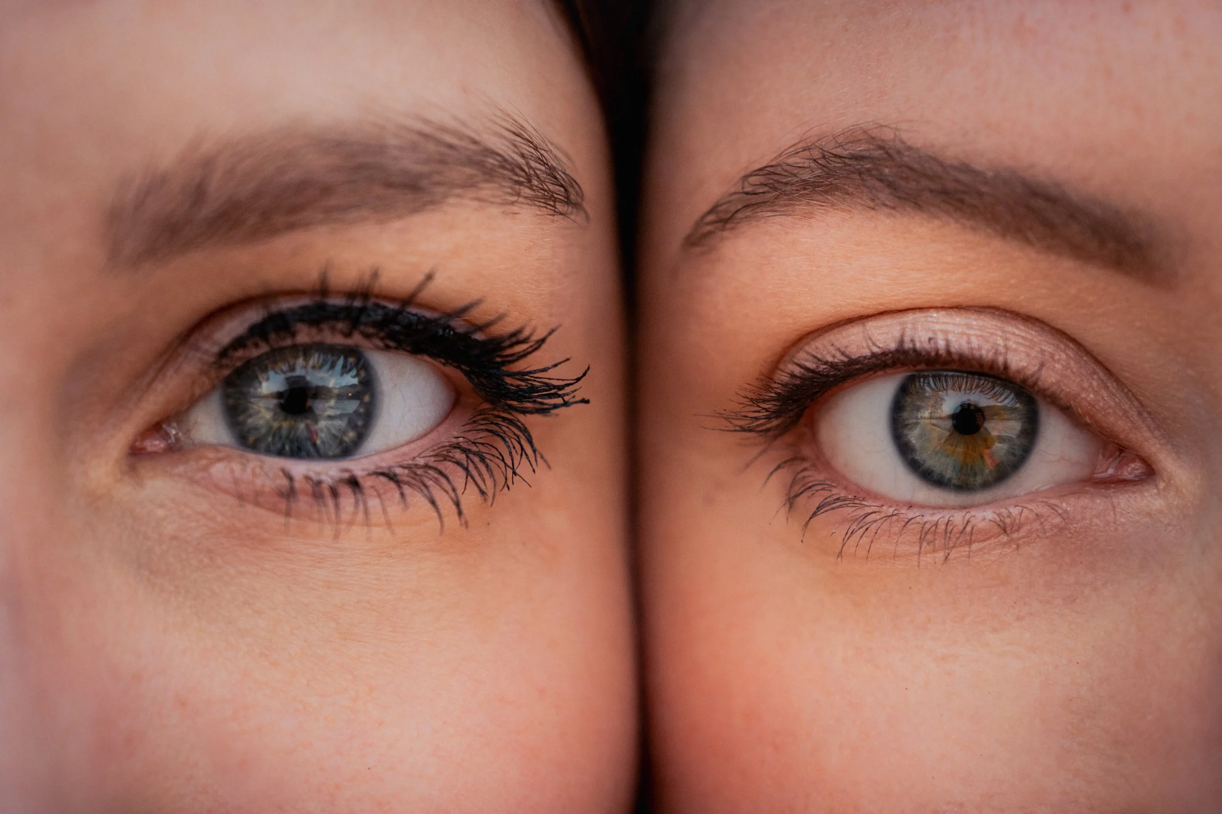 Nahaufnahme von zwei blauen Augen, die nebeneinander liegen, mit detaillierten Augenlidern und Wimpern.