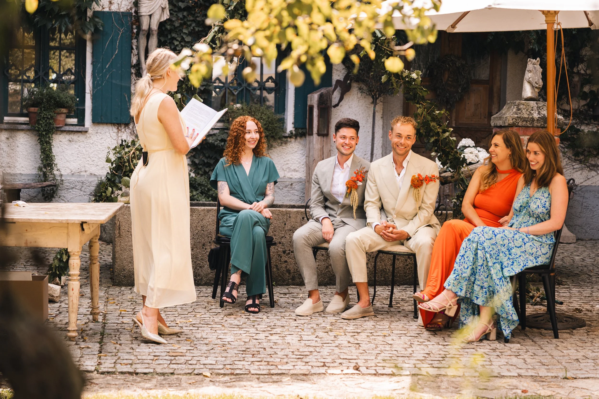 Eine frisch verheiratete Gruppe bei einer Trauung im Garten, bei der jemand die Ehe verspricht.