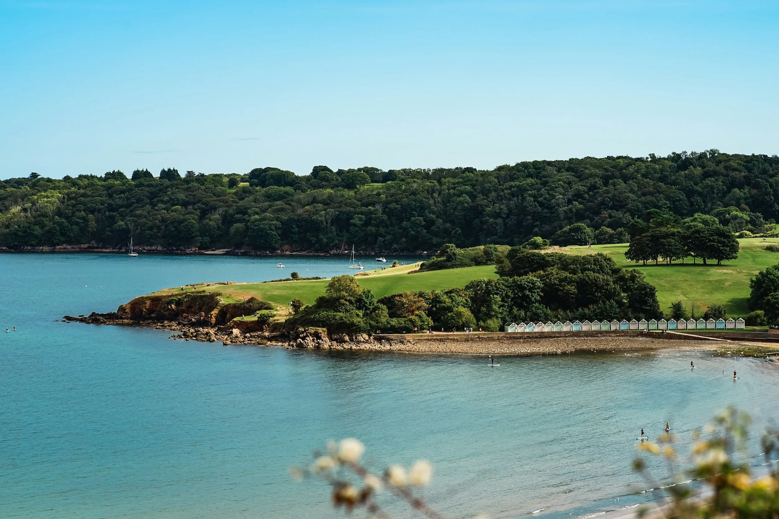 UK coastal scene with paddleboarders, sailing boats and beach huts, representing the marine environments Biotal Marine's products are designed to protect