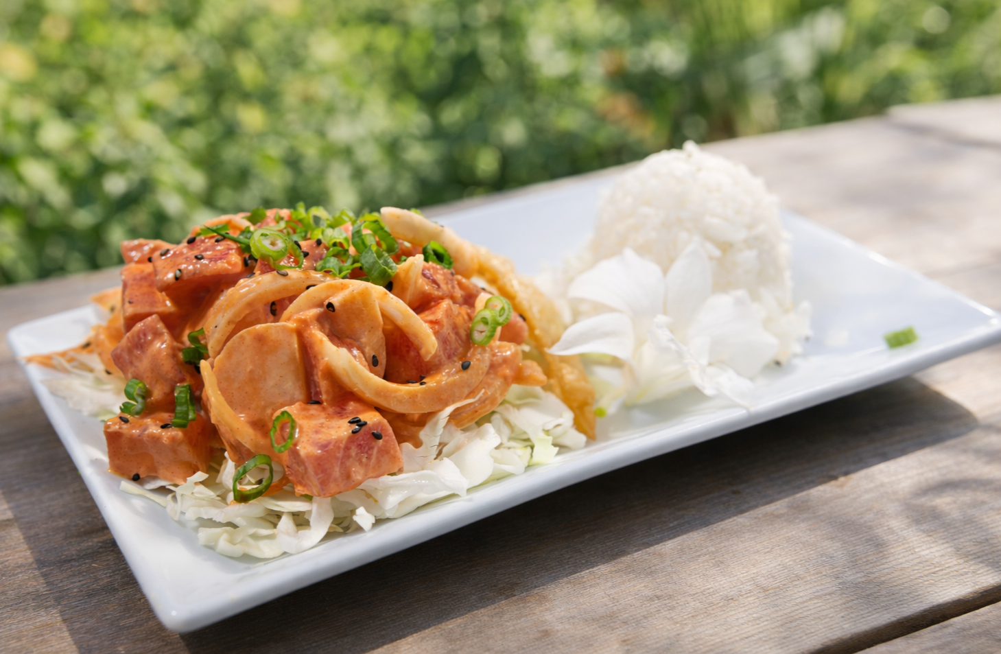 A plate of Mexican food featuring a crunchy taco filled with vegetables, surrounded by seasoned curly fries, shredded cheese, and a side of creamy green dipping sauce.
