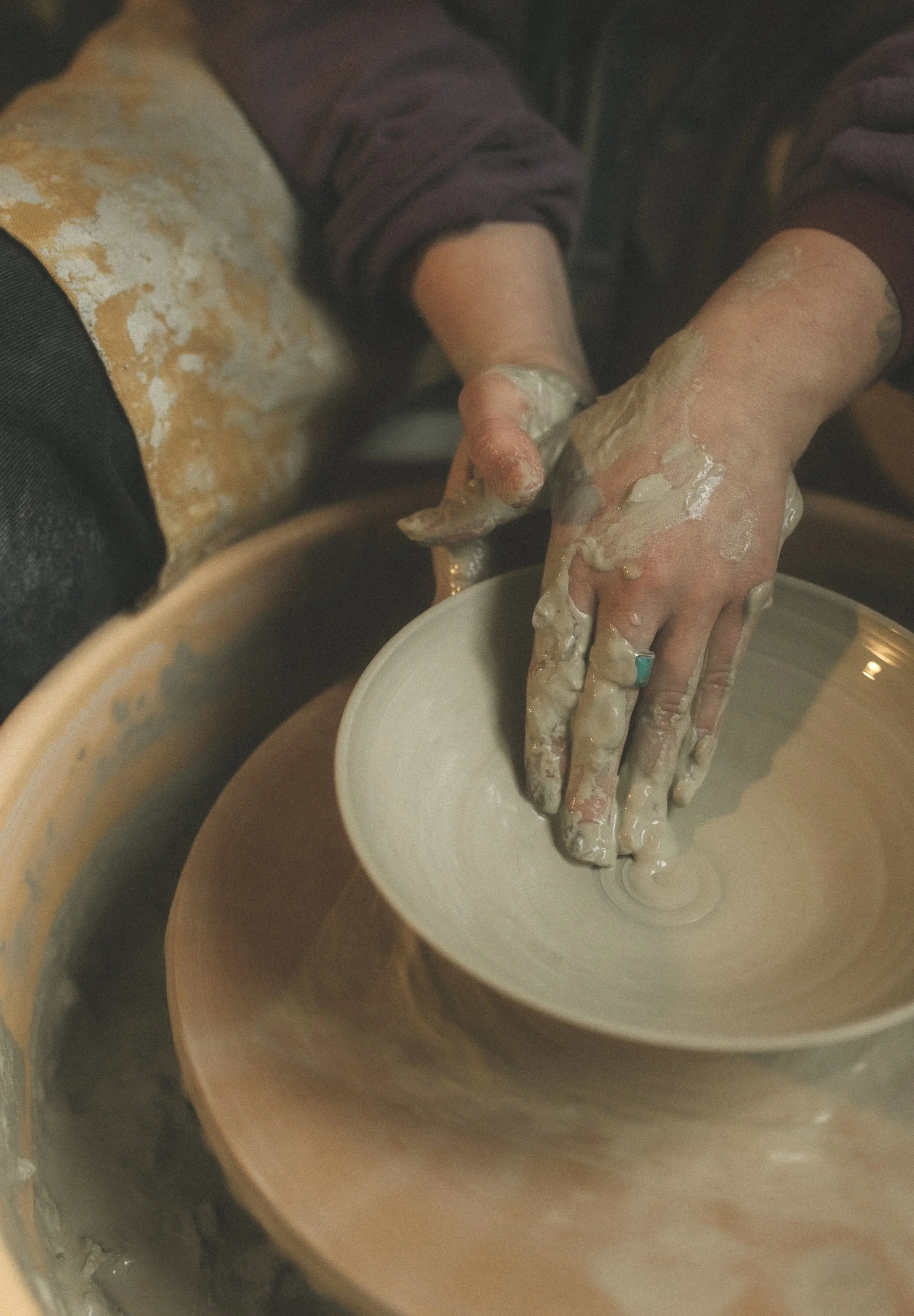 Eine Person formt handgefertigten Ton auf einer Töpferscheibe.