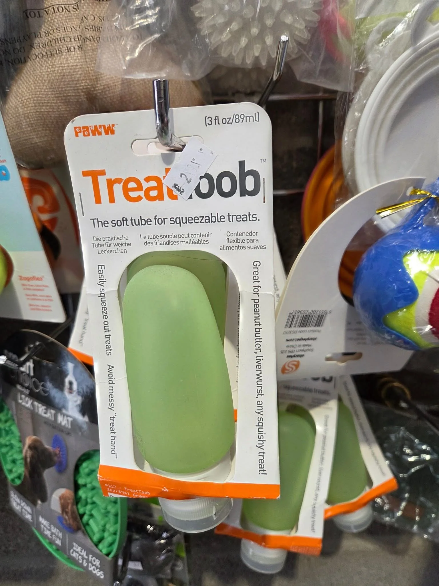 Green treat tube for squeezable pet treats, hanging on display in store.