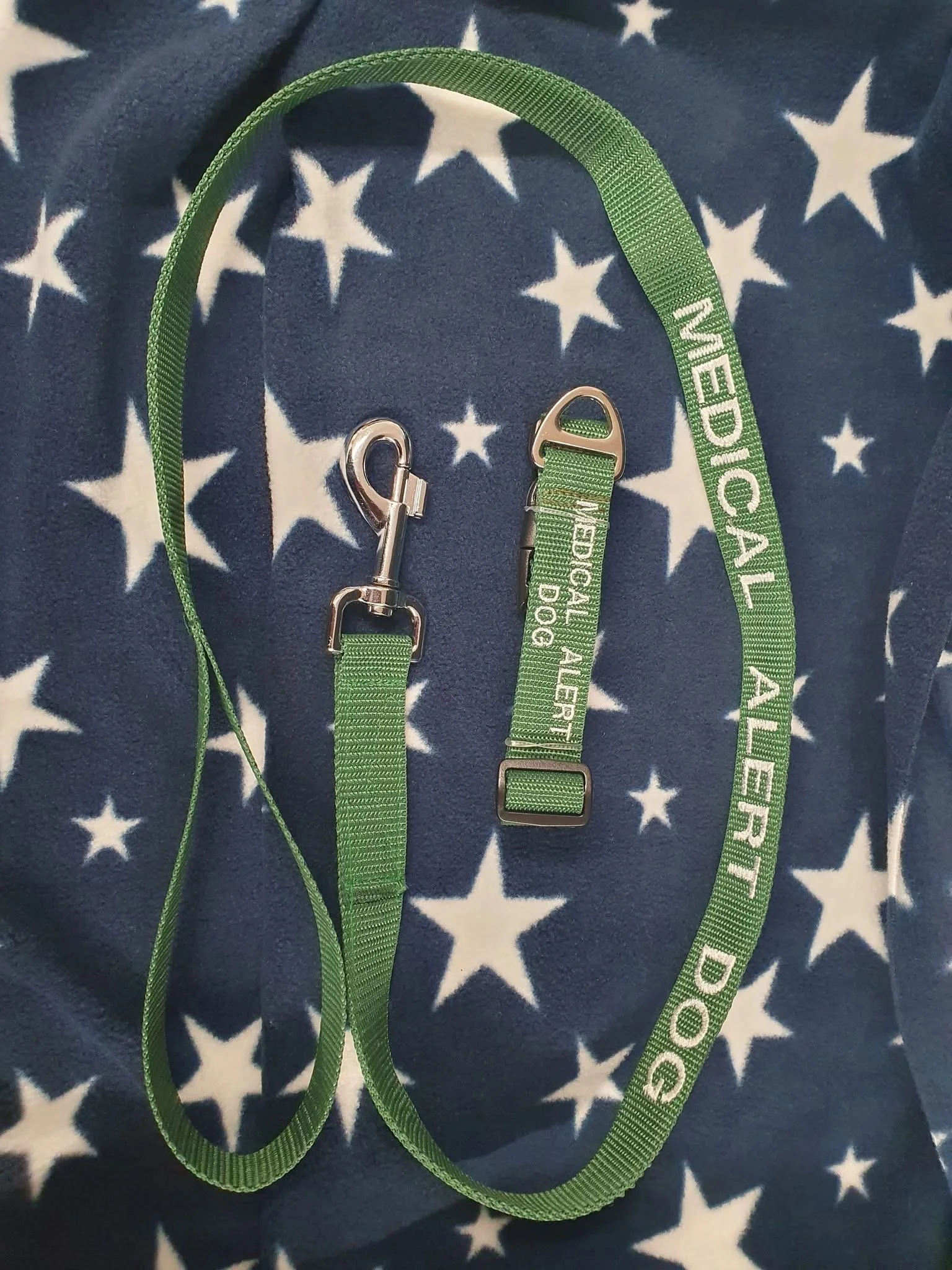 Green medical alert dog tag lanyard with a metal clip, placed on a blue fabric background with white stars.