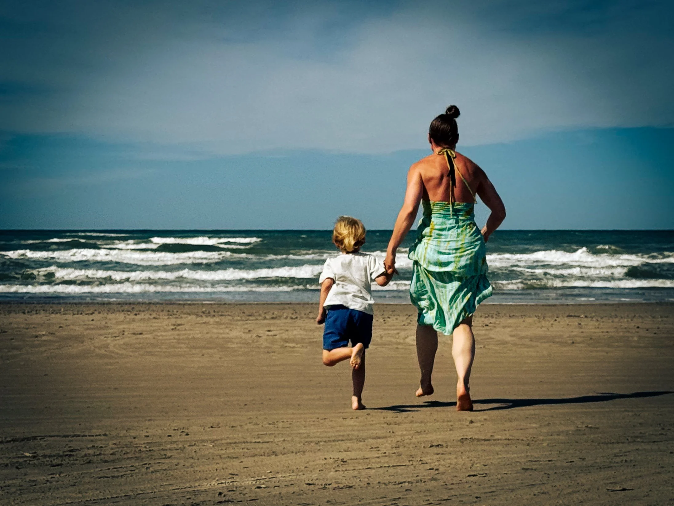 Mor og søn løber med glæde og overskud mod havet. Omsorg behandling af seniorer.