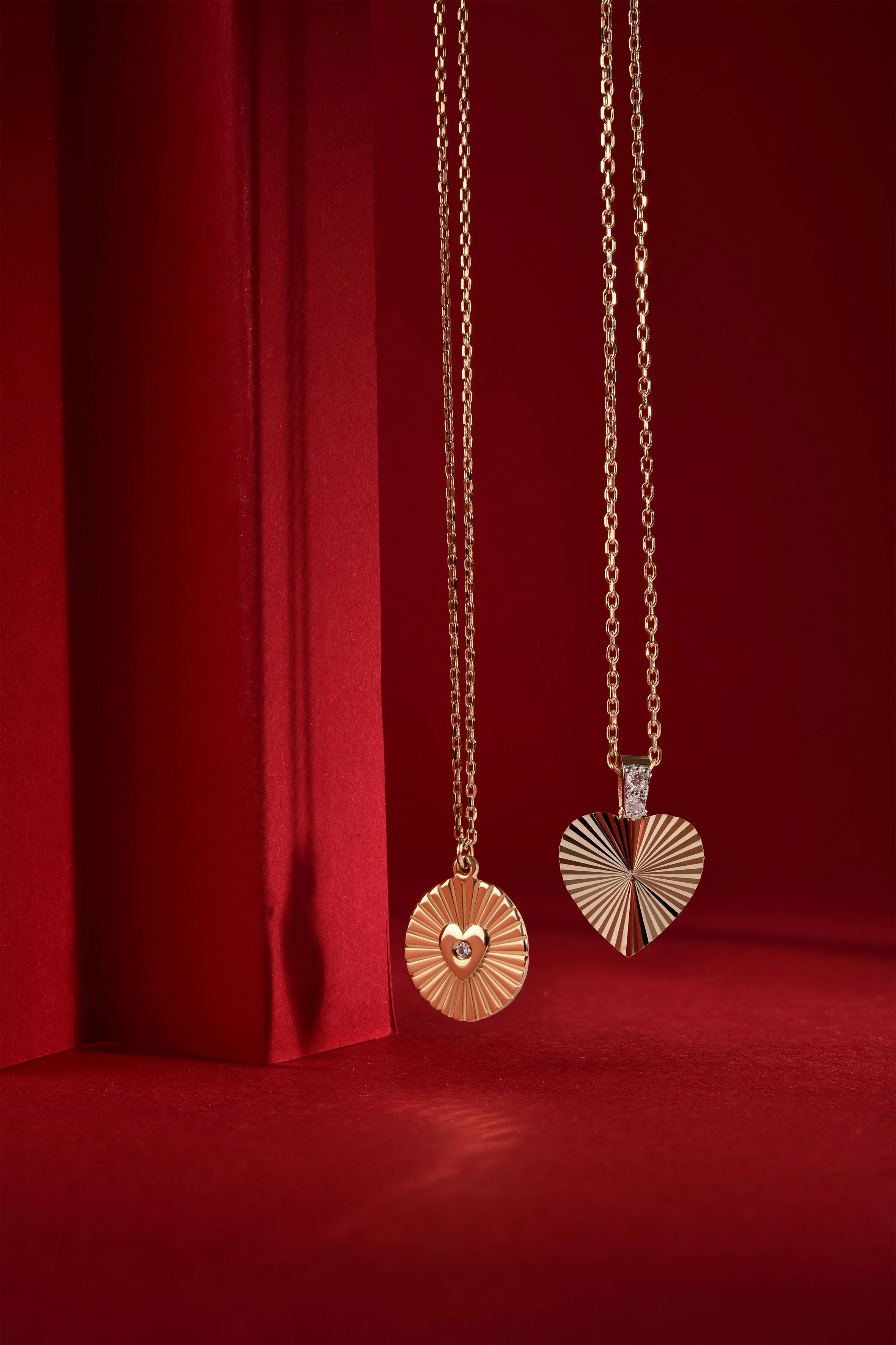 Pırlanta taşlı kalpli kolyeler, kırmızı zemin üzerinde