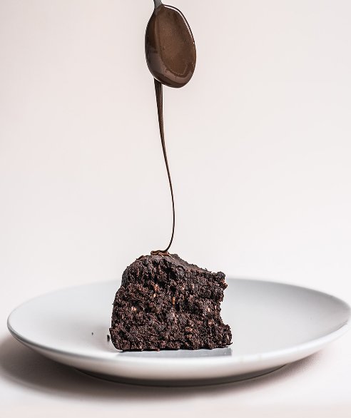 Photographie produit d’un gâteau au chocolat nappé de sauce fondue sur une assiette blanche — parfait pour du design culinaire et branding artisanal.