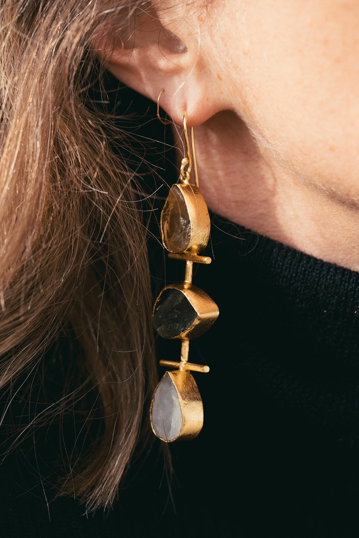 Photographie de bijou porté : boucle d’oreille suspendue en or avec pierres semi-précieuses — photo produit pour marque artisanale ou créatrice indépendante.