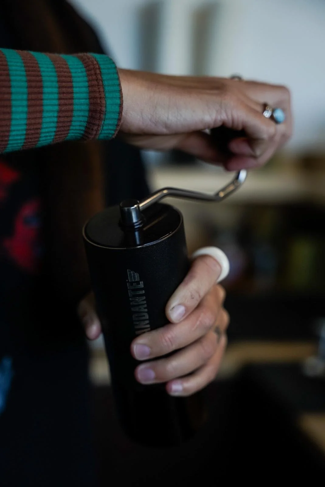 Main en train de moudre du café avec un moulin RODONIC visible — photographie de produit artisanale et storytelling autour du café.
