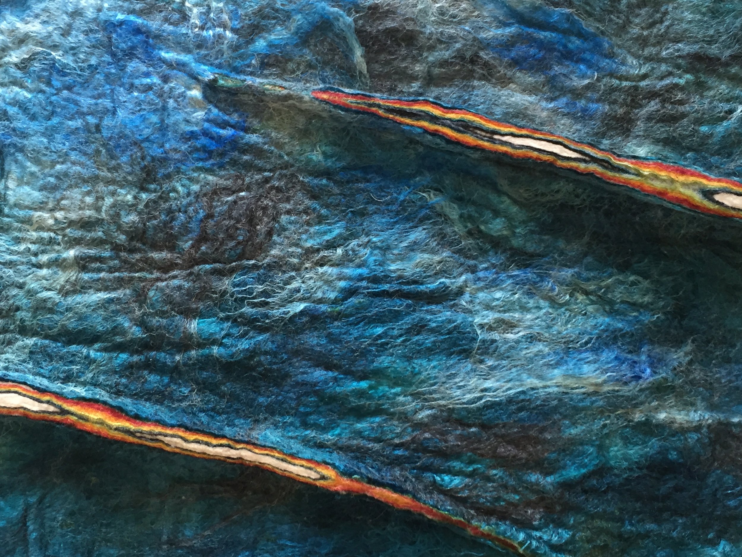 Close-up view of colorful textured fabric with blue, black, white, orange, and red hues.