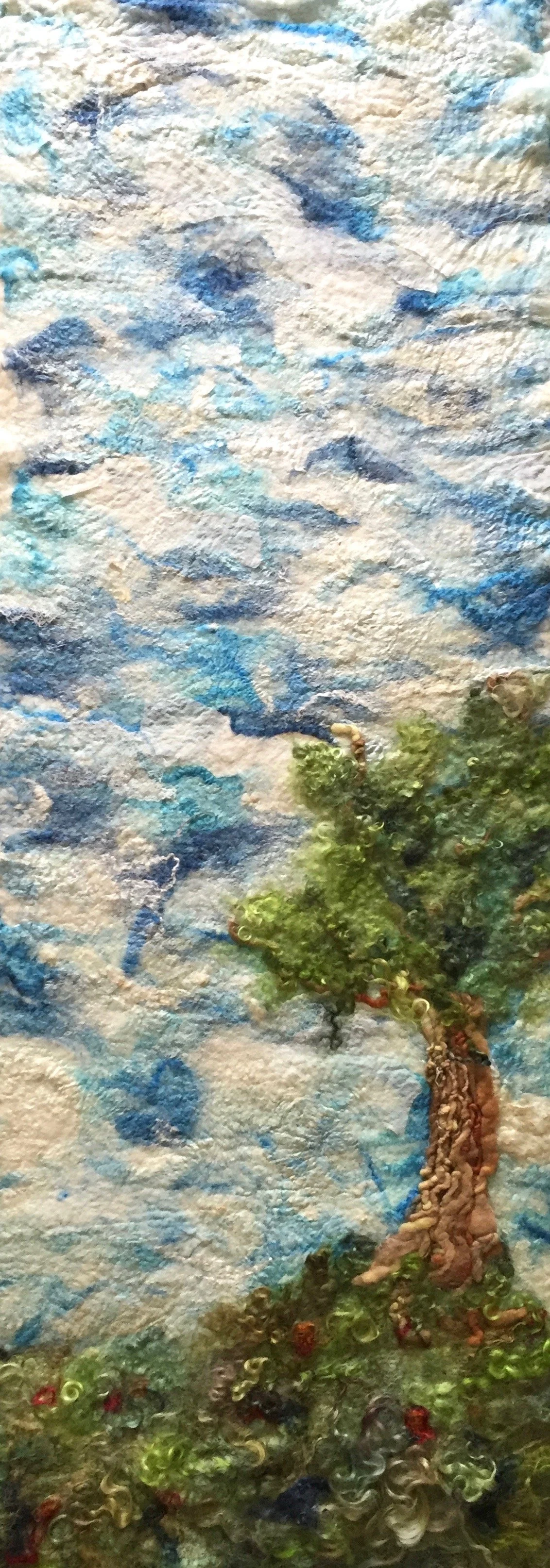 A mixed media art piece depicting a textured landscape with a tree made of layered materials and painted with vibrant colors, including blue, green, and brown.