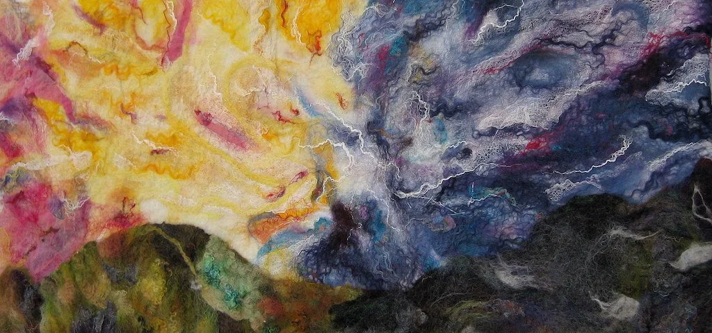 Abstract felt painting with vibrant yellow, pink, and red clouds on the left and dark blue, purple, and black clouds with lightning on the right over green mountain peaks.