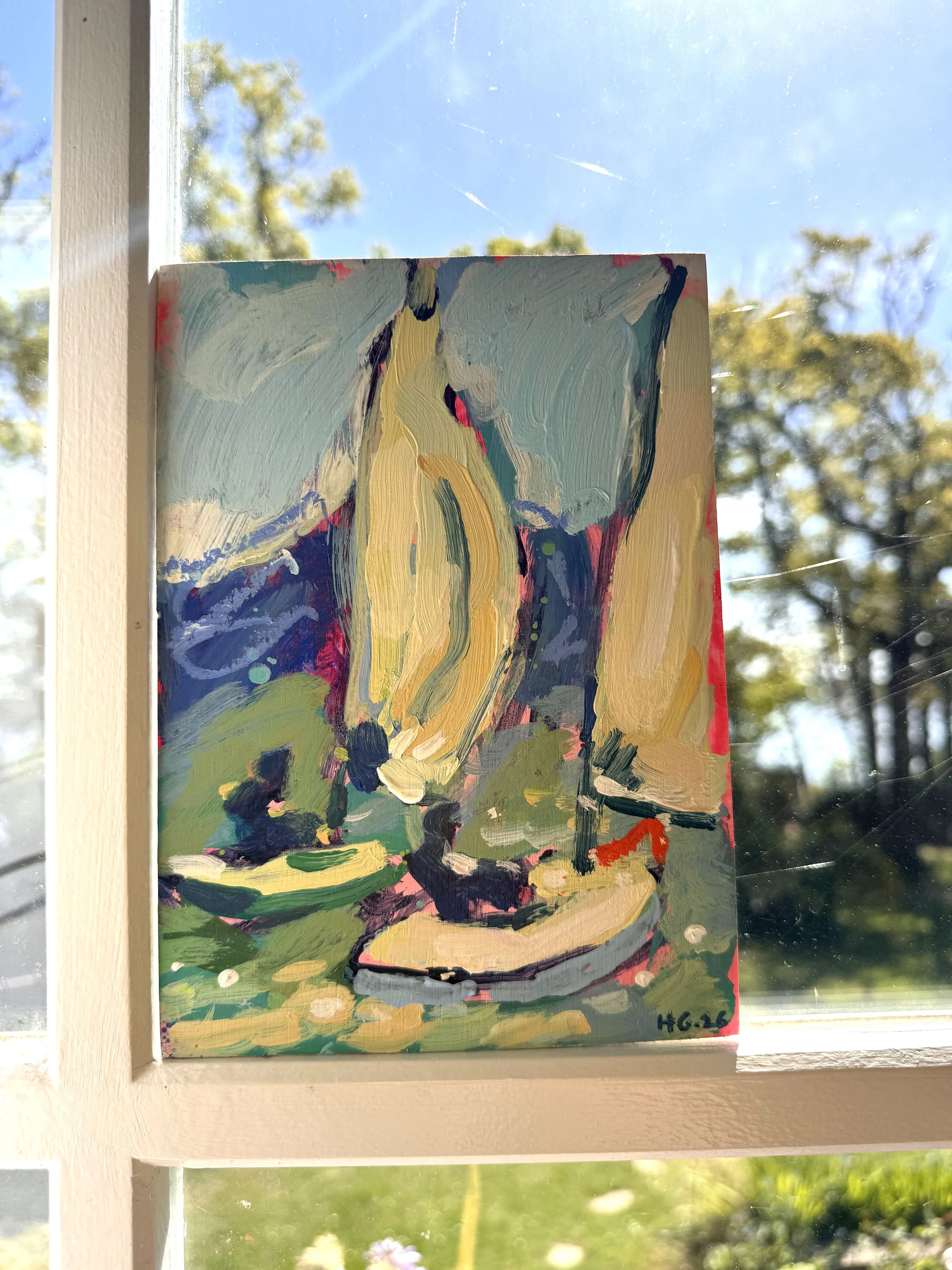 An abstract impressionist painting of a landscape with a large yellow and green tree, a blue sky, and a purple and black ground, mounted on a window by a white frame with sunlight streaming through, with trees and a blue sky visible outside.