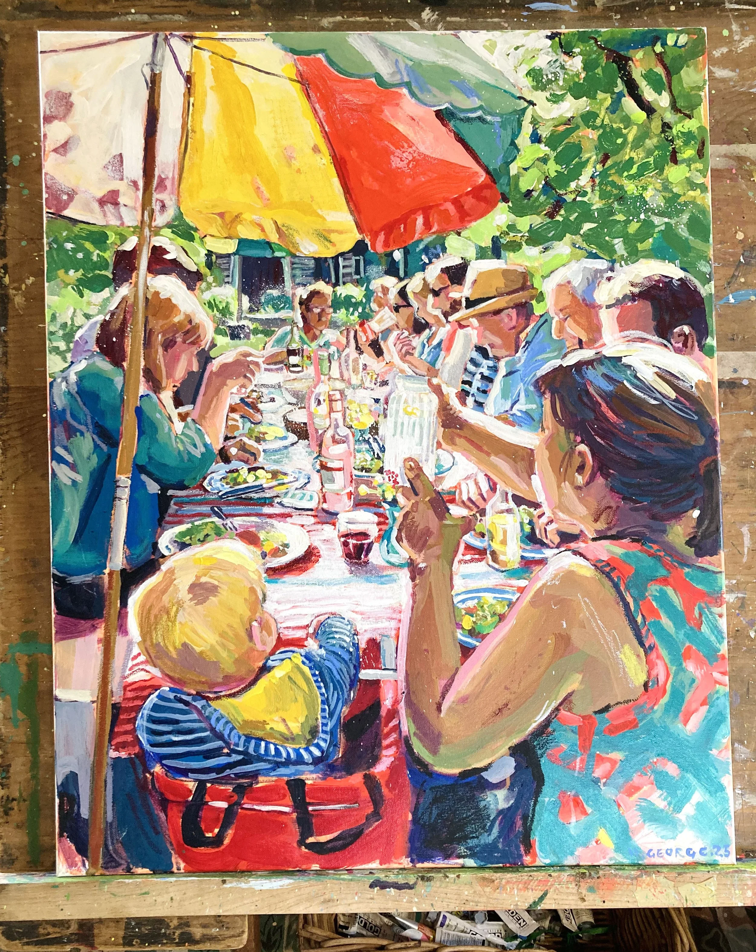 Colorful impressionistic painting of a group of people sitting around a table outdoors under a large yellow and red umbrella with green foliage in the background, painted in vibrant brushstrokes.