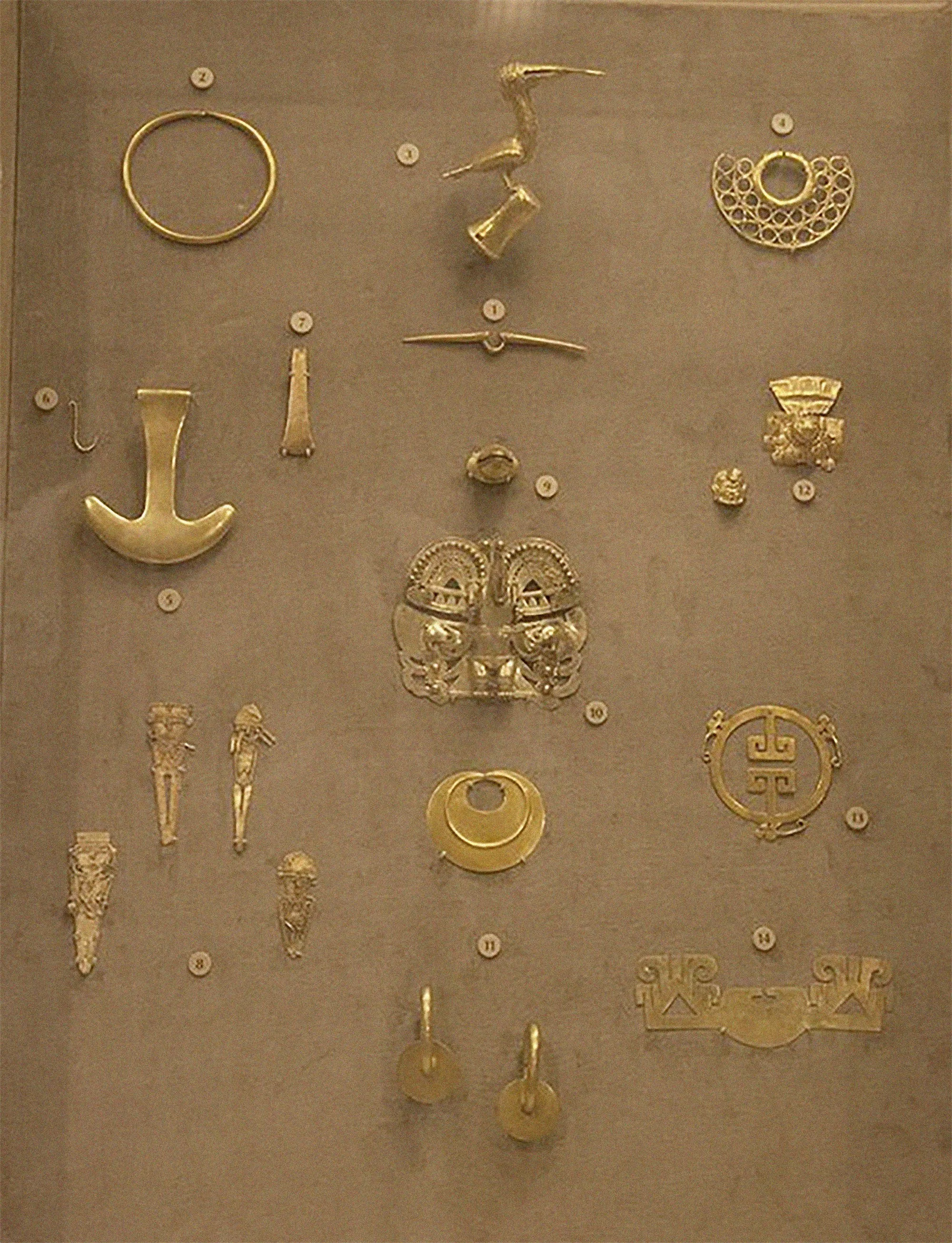 Collection of ancient gold artifacts including jewelry, pendants, and decorative objects displayed in a museum case.