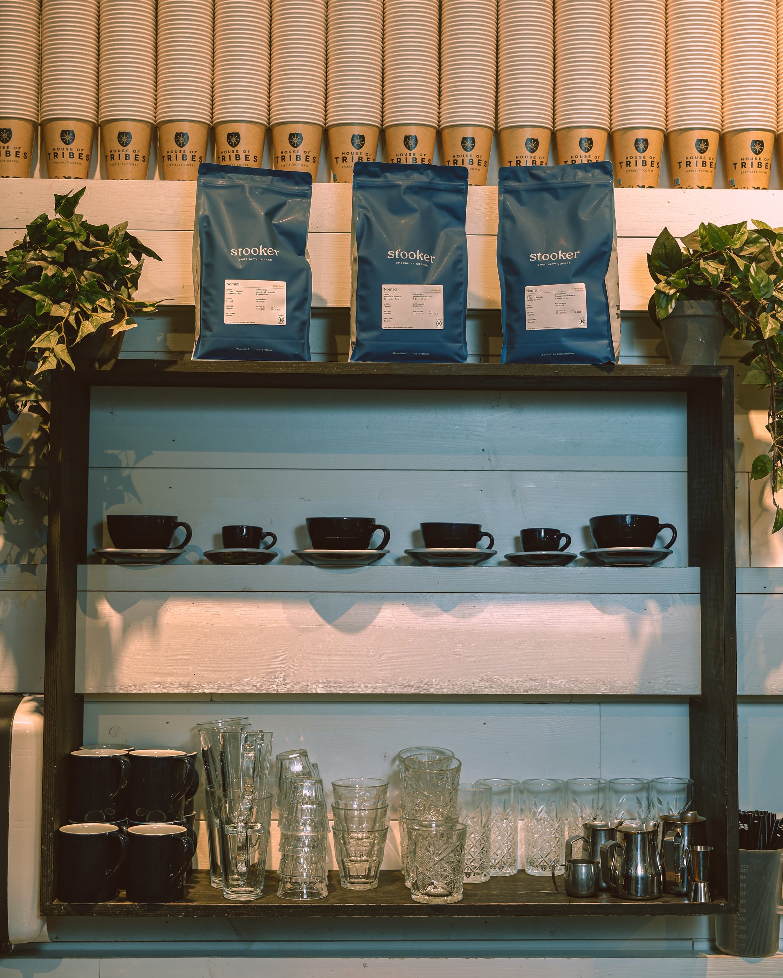 Shelves with coffee cups, glasses, and bags of coffee beans in a cafe.
