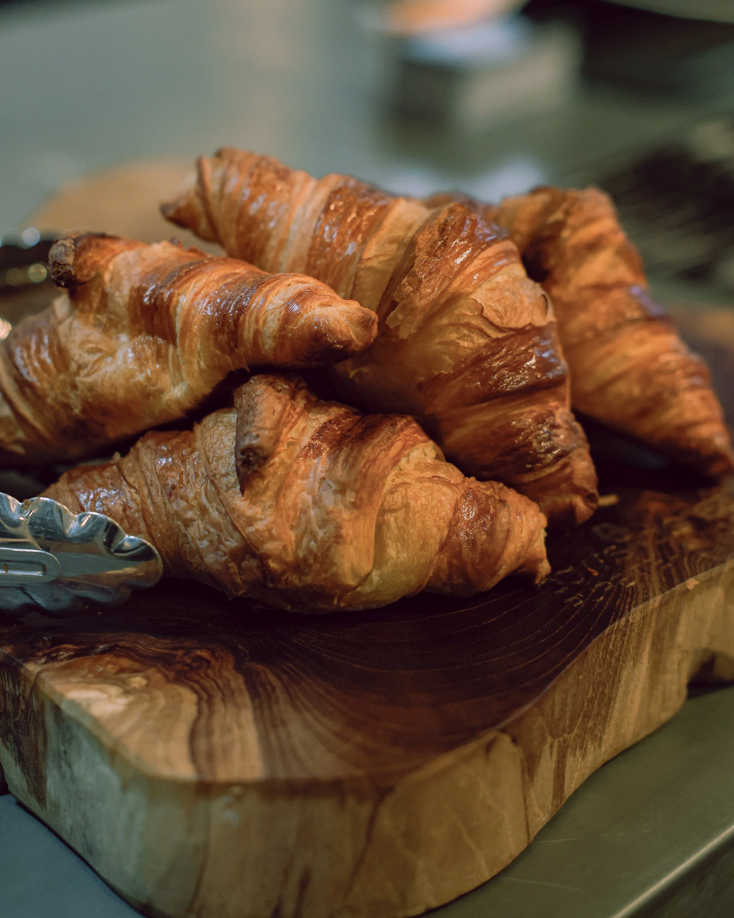 A batch of croissants on a wooden cutting board.