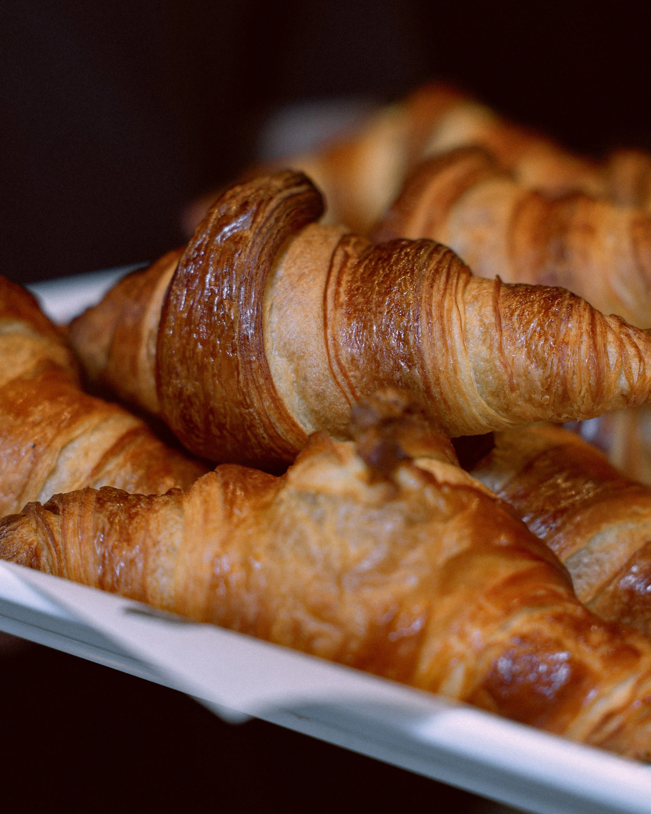 Close-up of golden-brown croissants on a white plate.