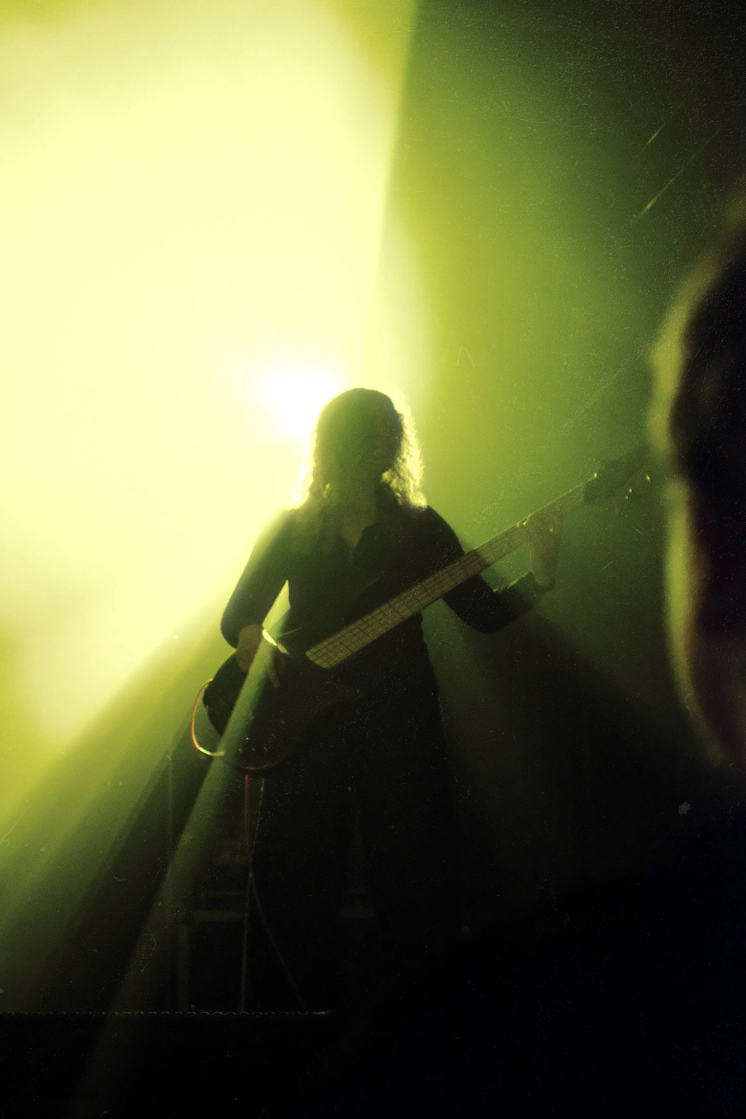 Silhouette of a person playing an electric guitar on stage with green lighting