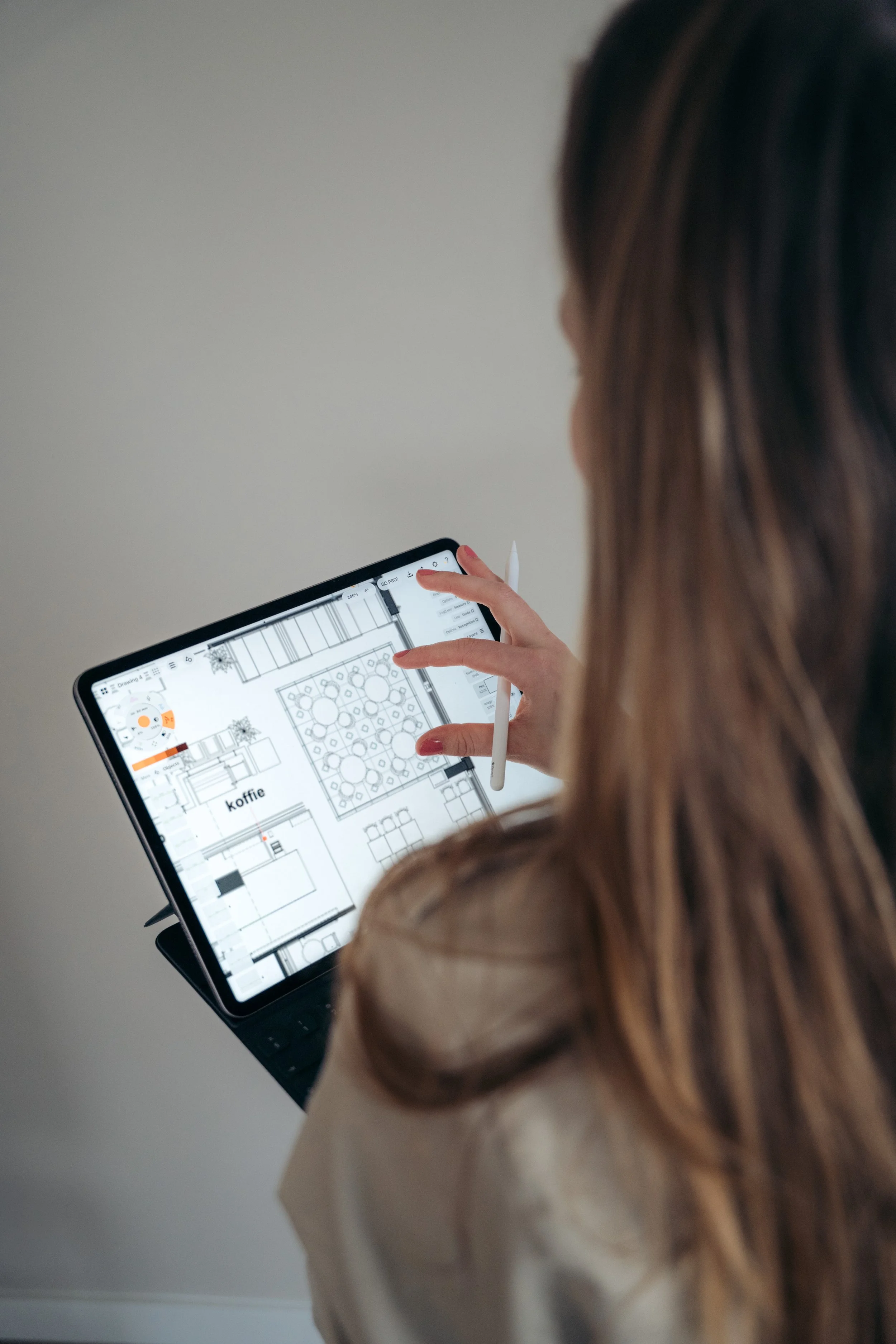 Vrouw die een plattegrond op een tablet bekijkt en een stylus vasthoudt.