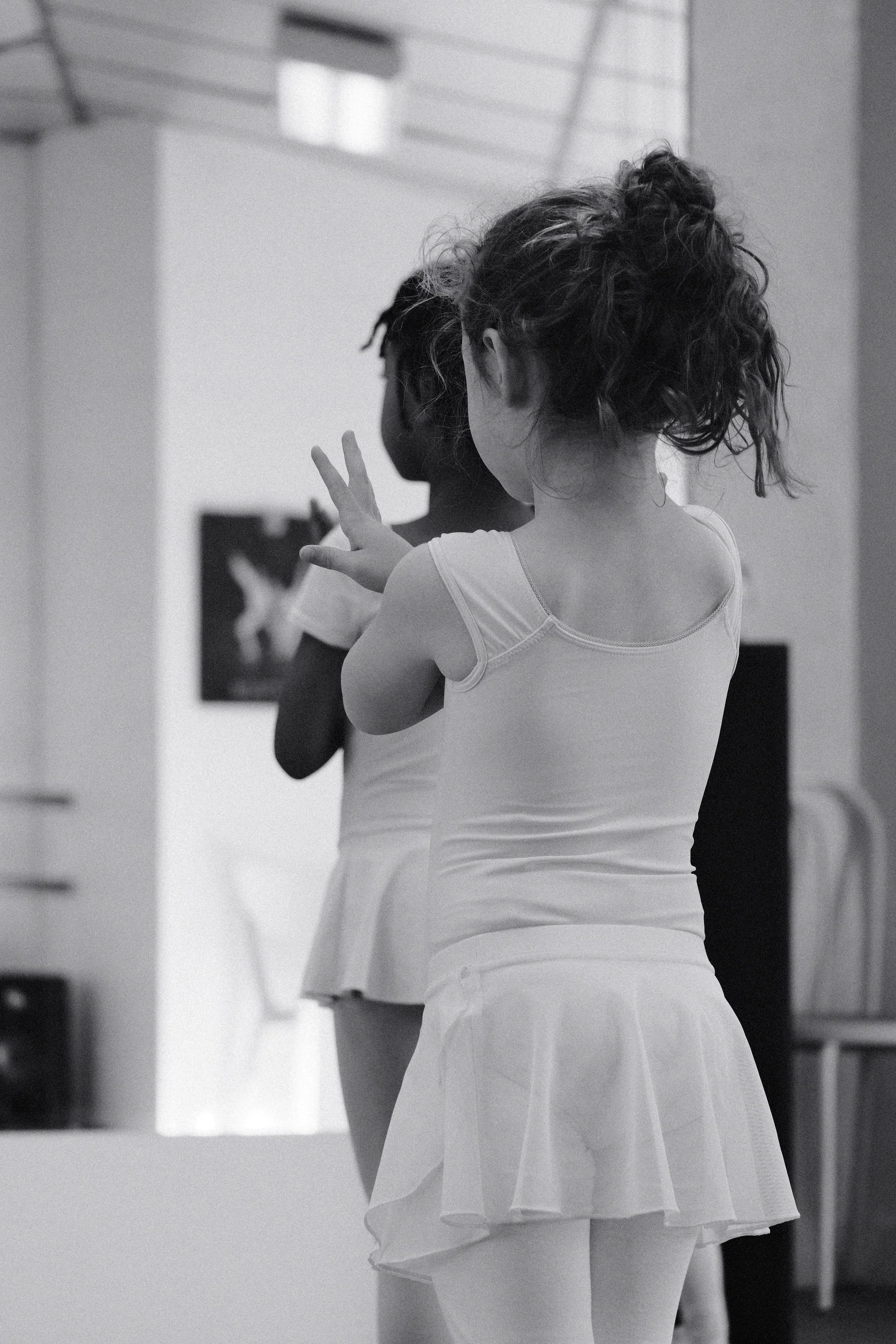 Deux jeunes filles habillées en justaucorps de  danse observant un miroir, en studio de danse.