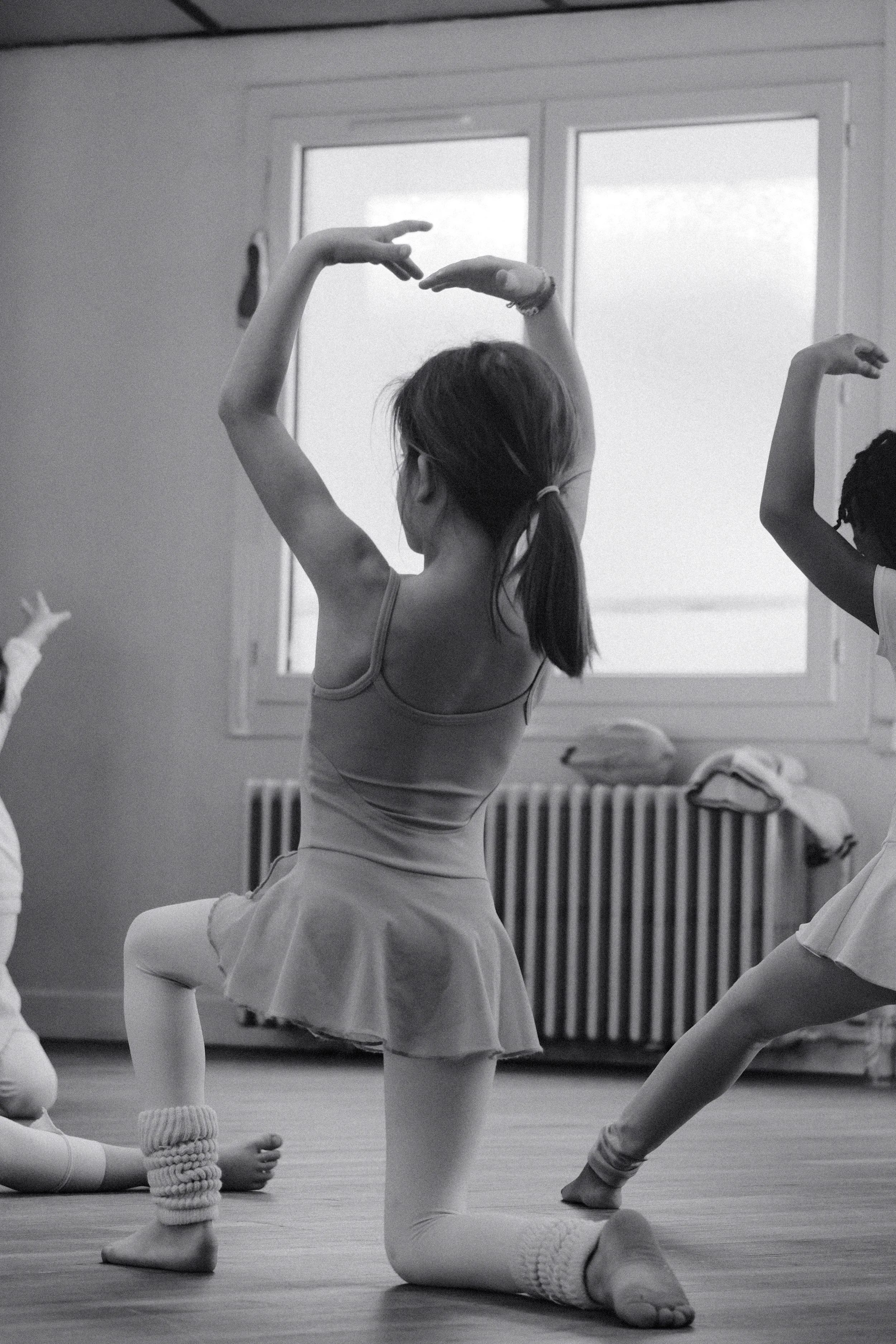 Une jeune fille fait de la danse dans une salle d'entraînement, vue de dos.