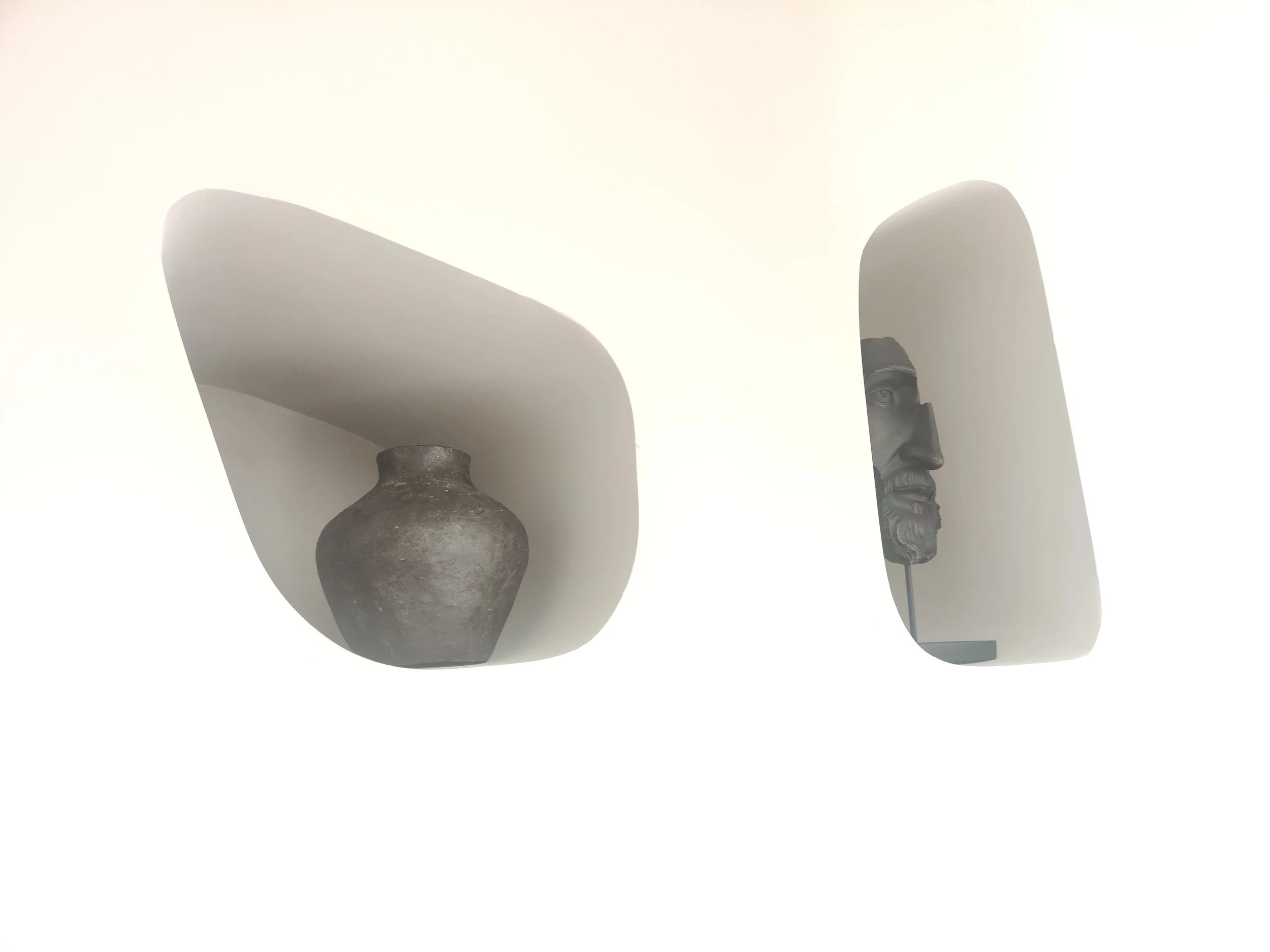 A ceramic vase with a narrow neck and a round body, placed on a white surface against a white background.